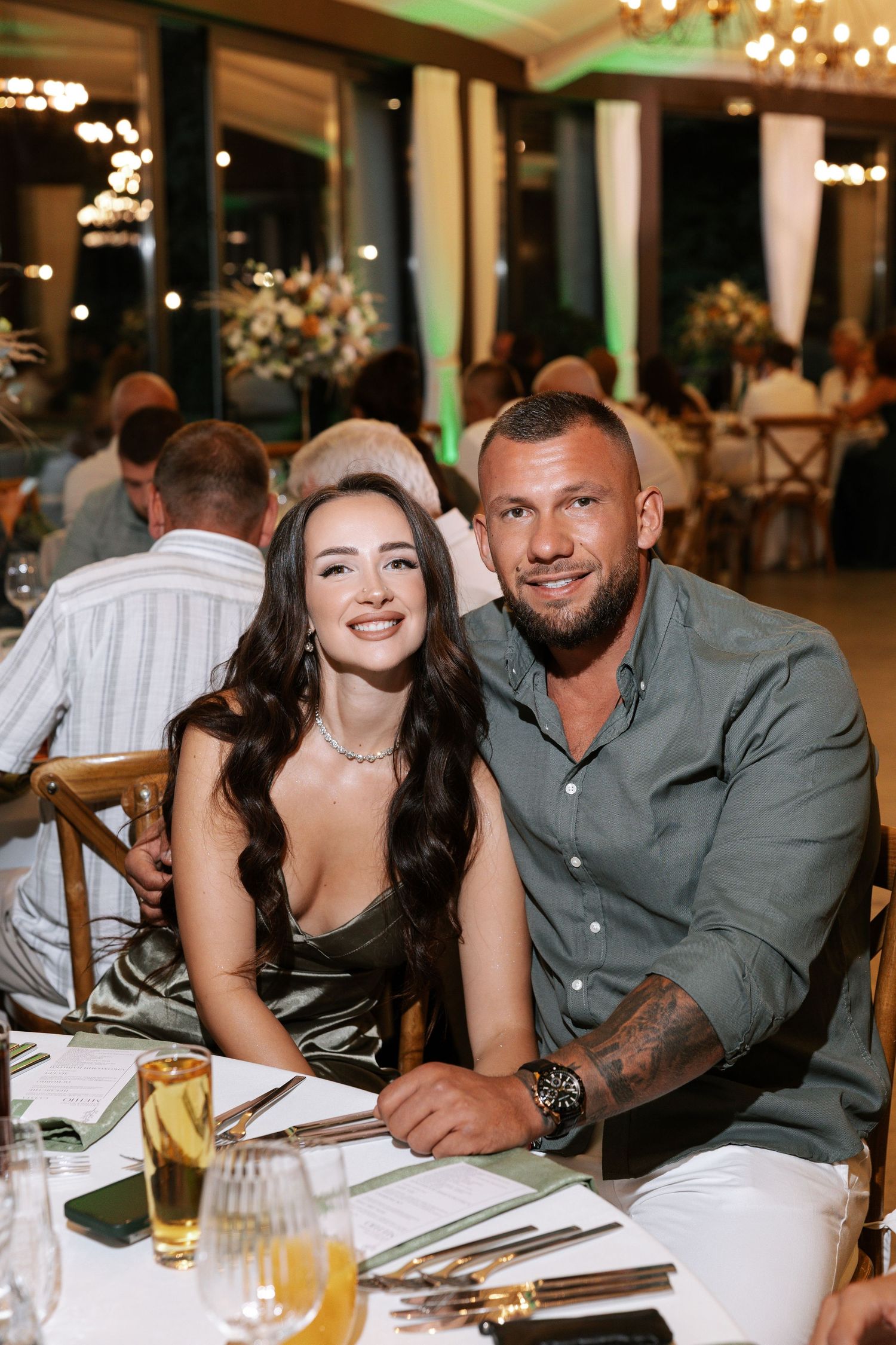 A couple enjoys an elegant dinner at an upscale restaurant with mood lighting and table settings.