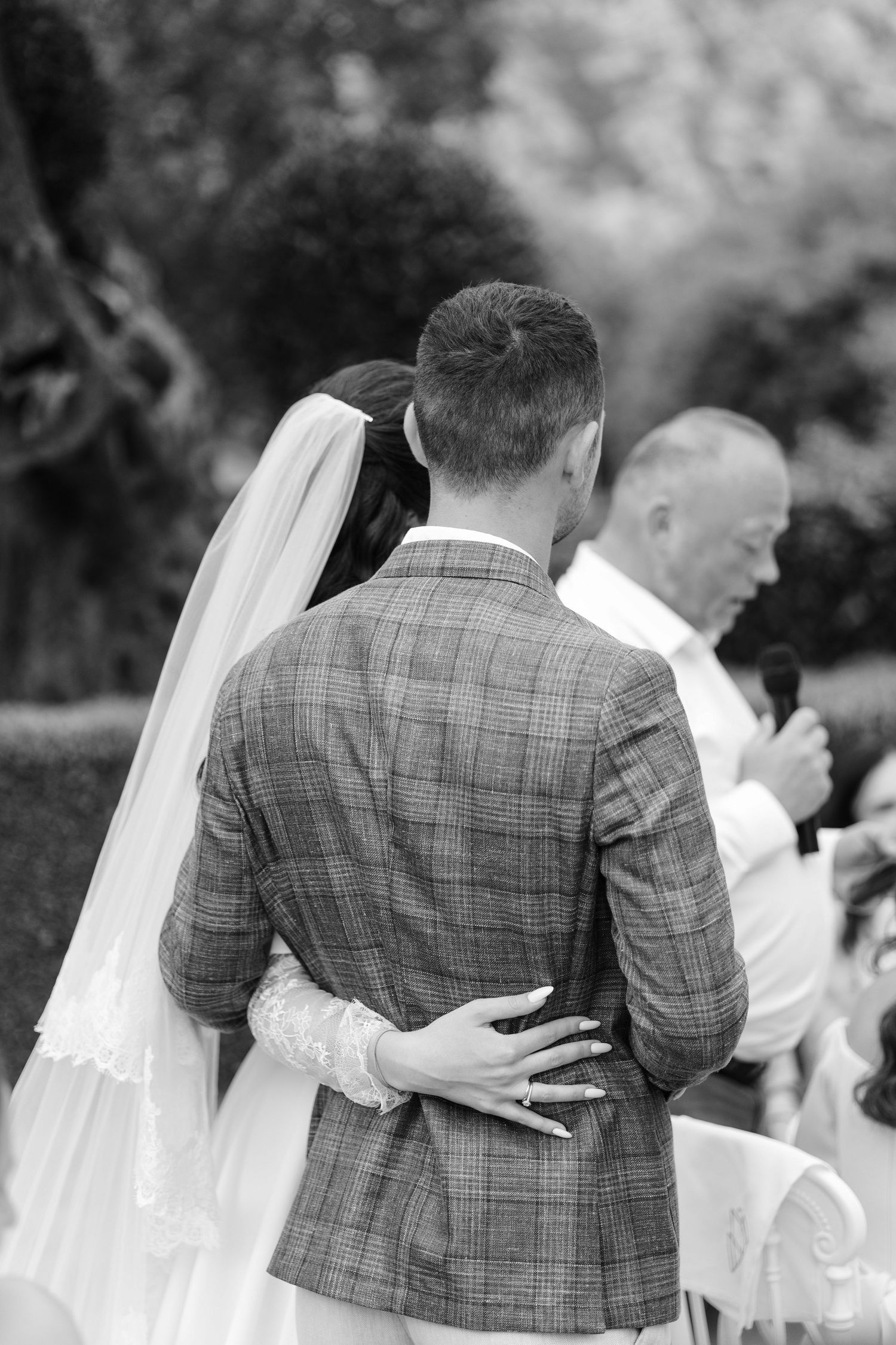 Black and white photo of couple embracing during wedding ceremony.