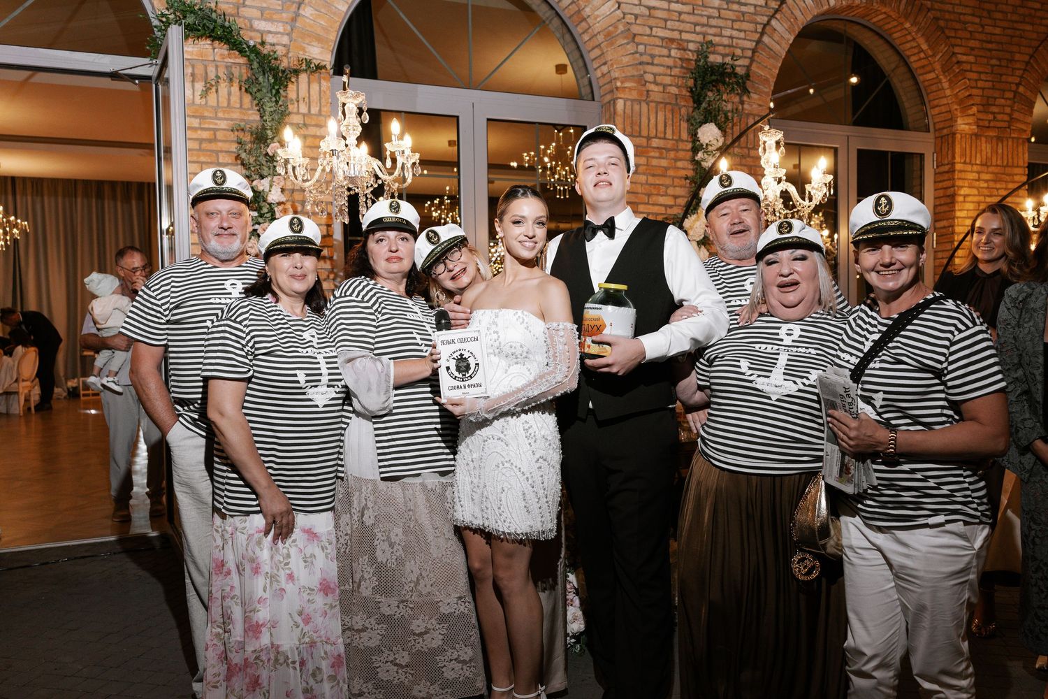 Wedding party wearing striped shirts and casual attire dancing at an indoor reception.
