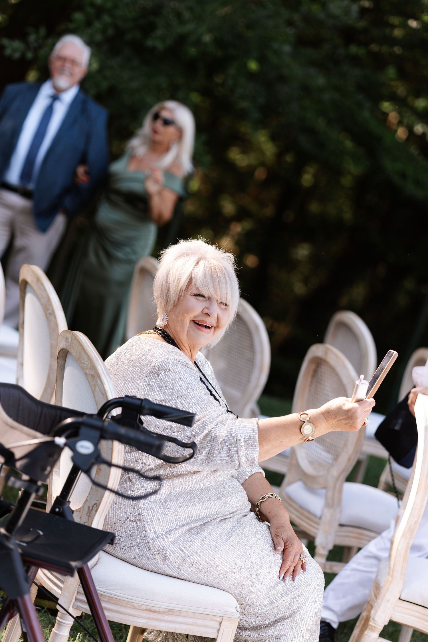 Wedding guest seated in white chair at outdoor ceremony using mobility walker.
