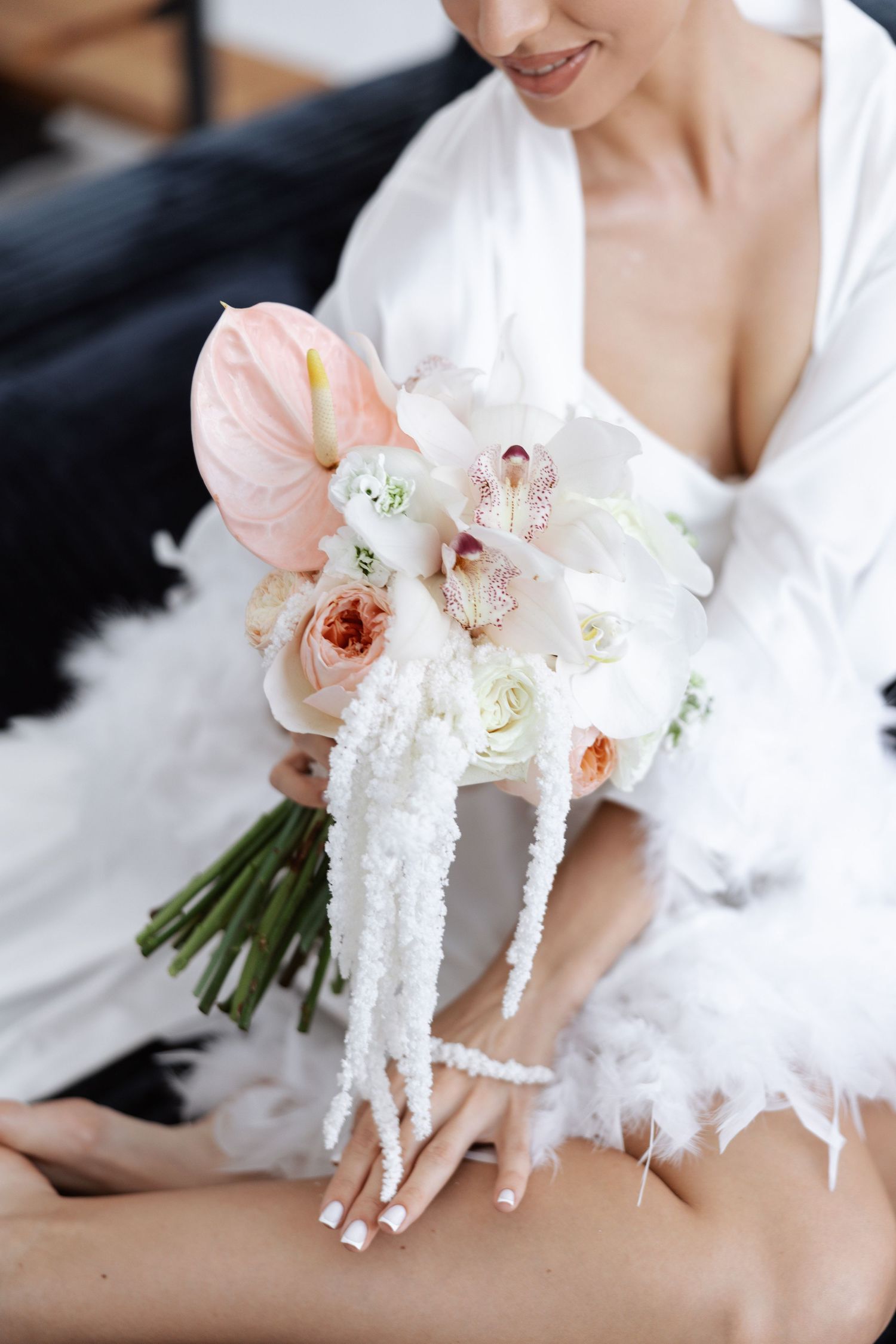 An elegant bridal bouquet features pink orchids and white roses with delicate cascading details.