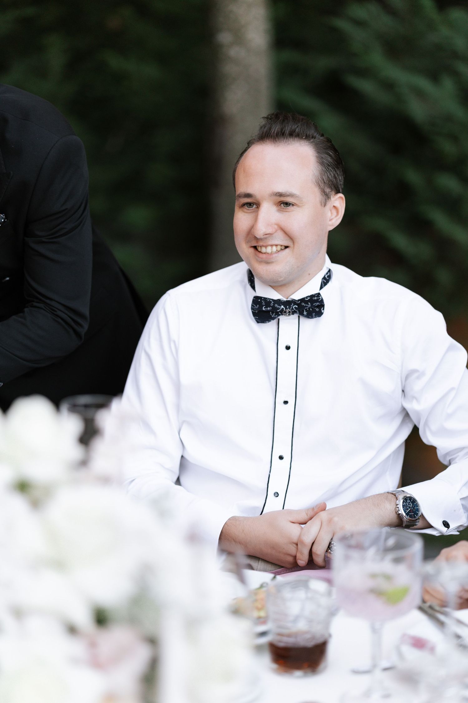 Close-up of formal attire with white shirt and black bow tie at wedding reception.