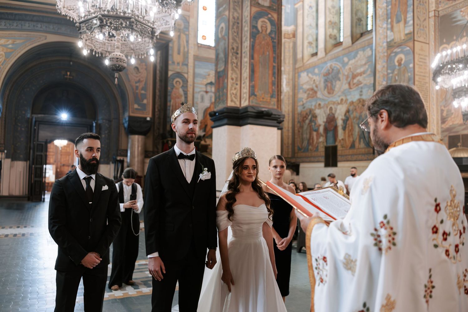 Orthodox wedding ceremony with priest in embroidered vestments conducting service in historic church.