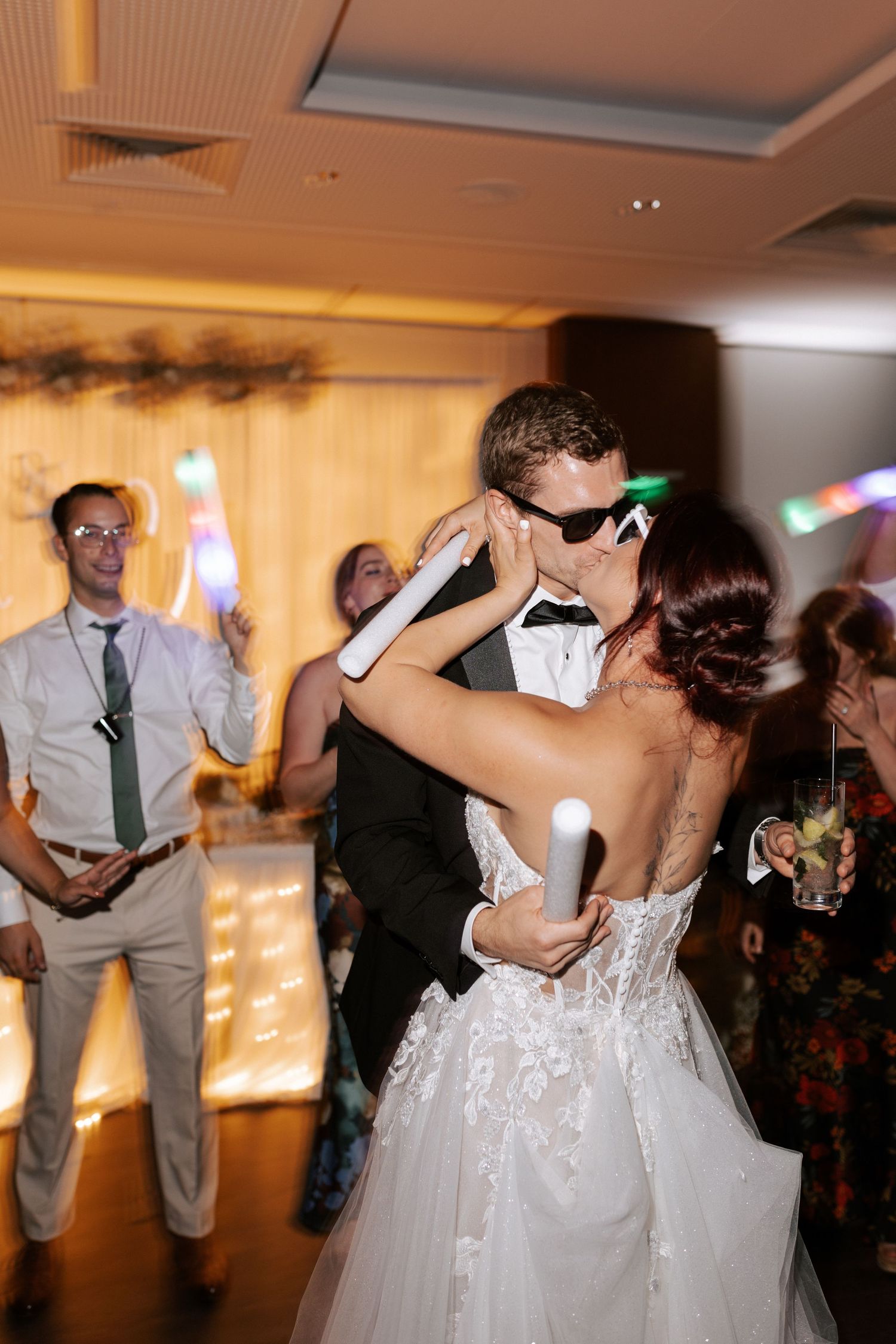 Couple shares an intimate dance moment while holding light-up party favors at their wedding reception.