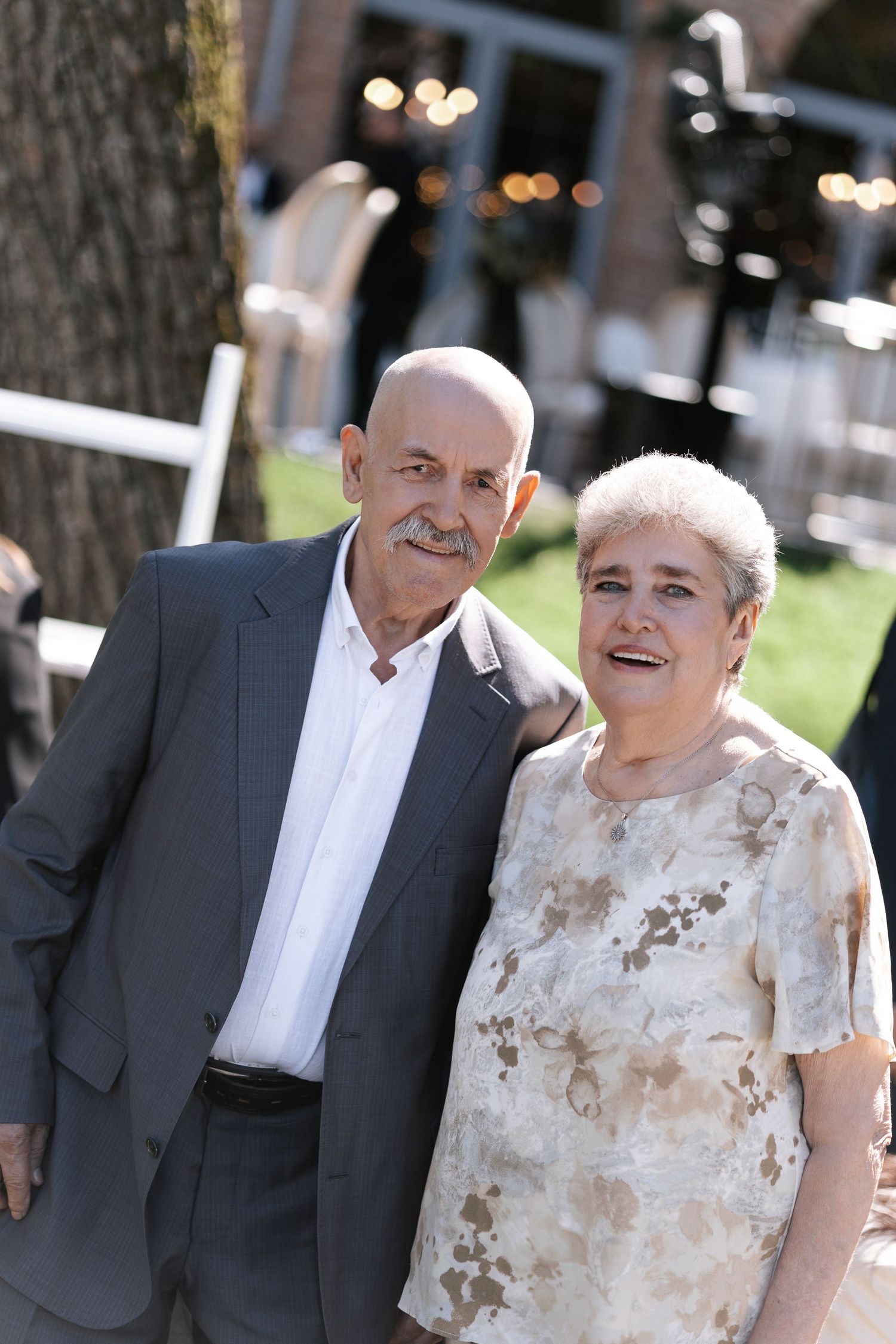 Mature couple in formal attire posing together outdoors.