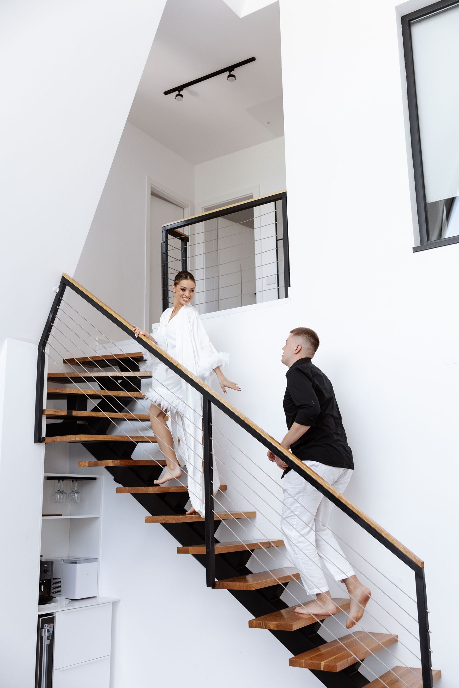 Modern wooden staircase with white walls and black railing shown in multiple angles.