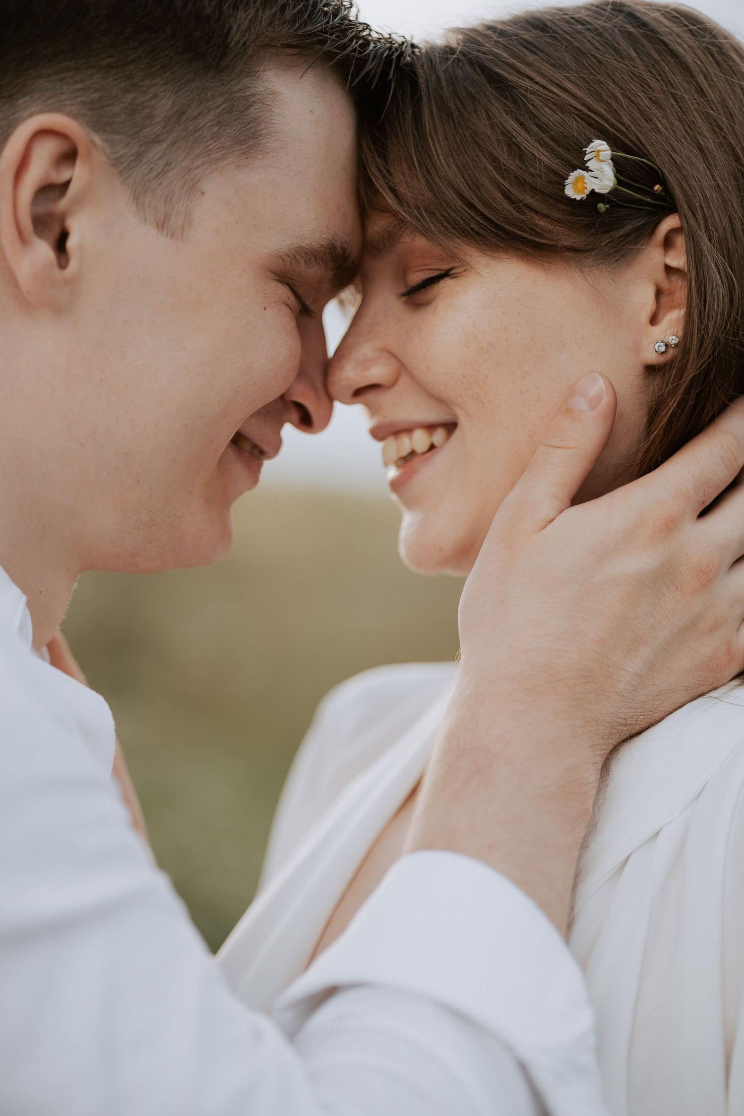 Intimate close-up of couple sharing tender moment with butterfly hair clip detail.