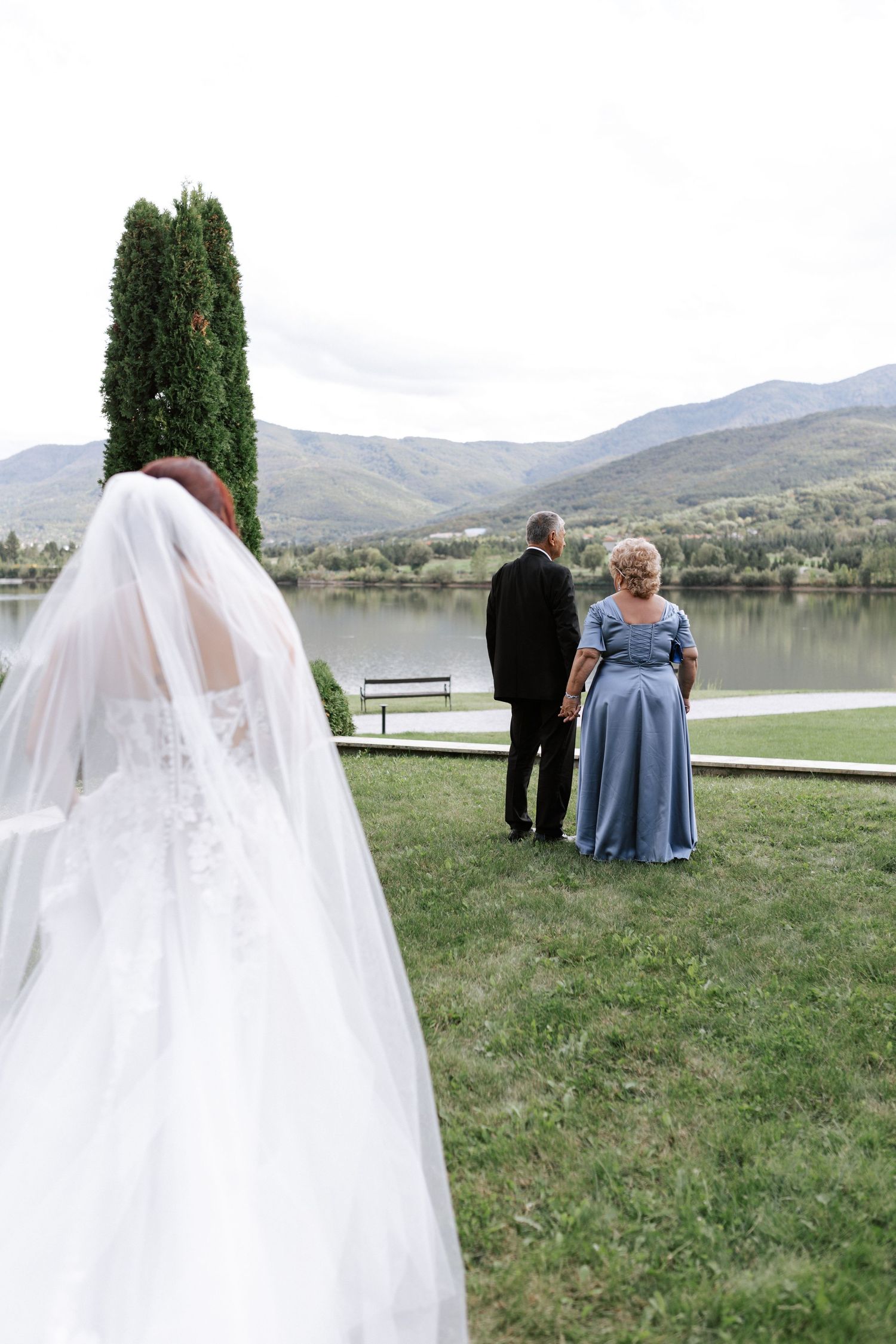 Wedding scene by lake with flowing white veil in foreground.