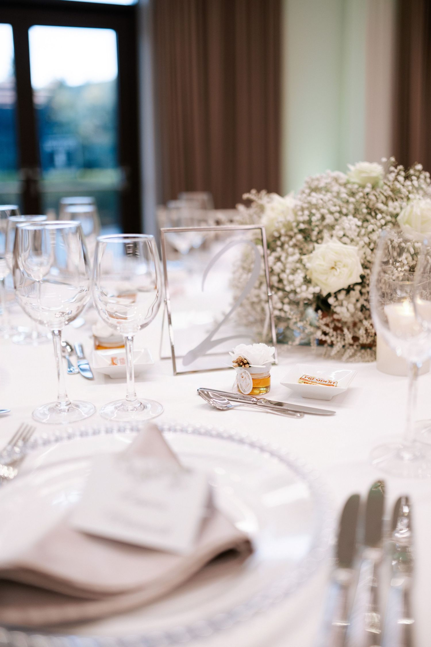Elegant wedding reception table setting with white flowers, wine glasses, and delicate place settings.