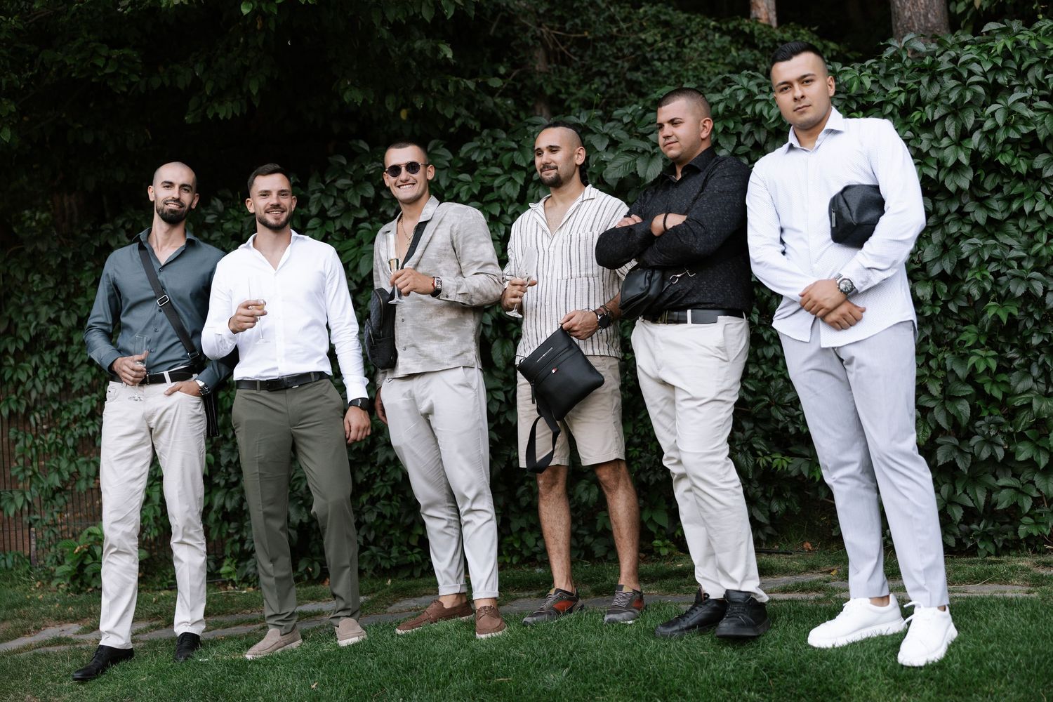 Group of people in white and casual attire sitting together on outdoor steps in a relaxed setting.