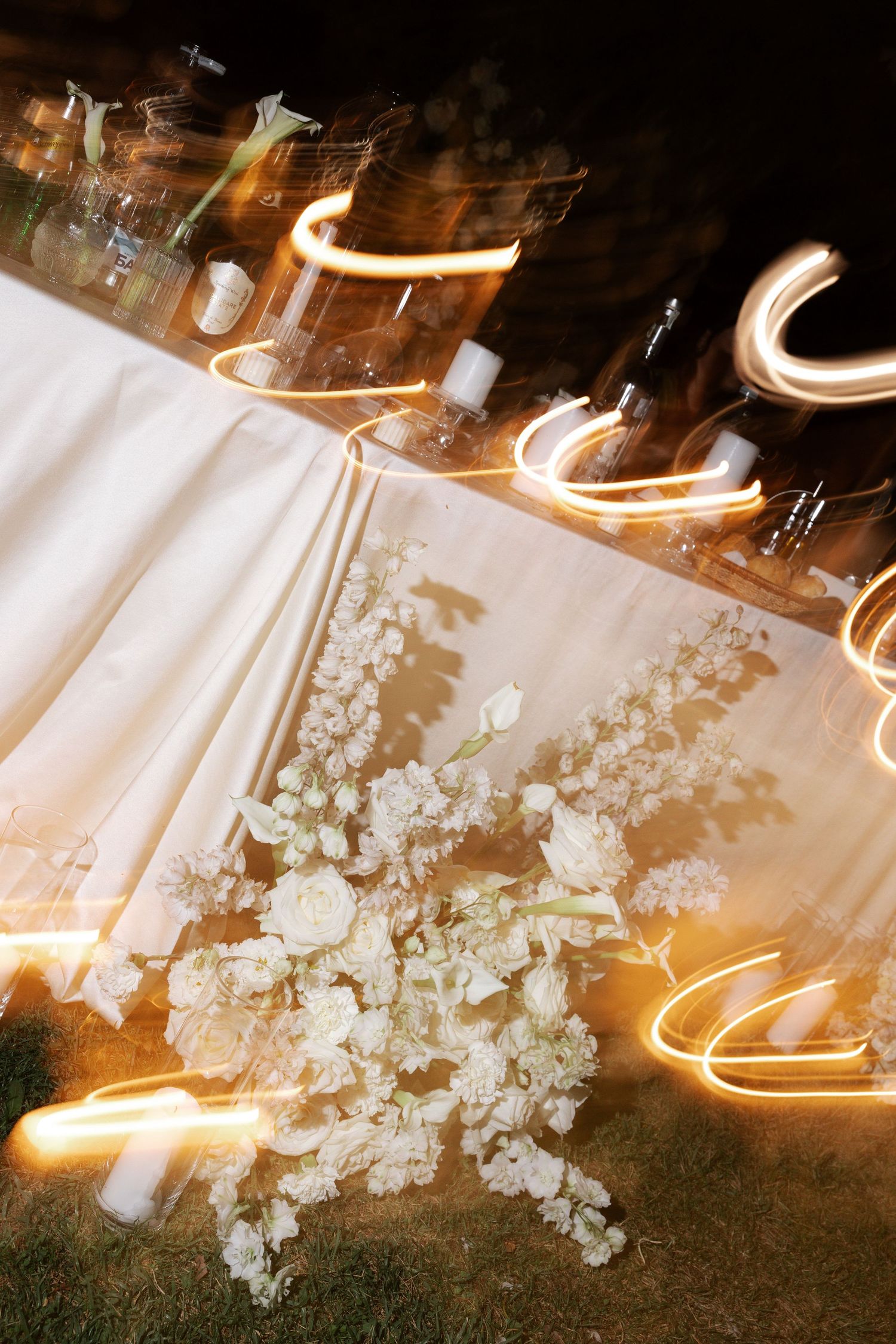 Long exposure photograph of light trails swirling around white cherry blossoms at night creating a dreamy effect.