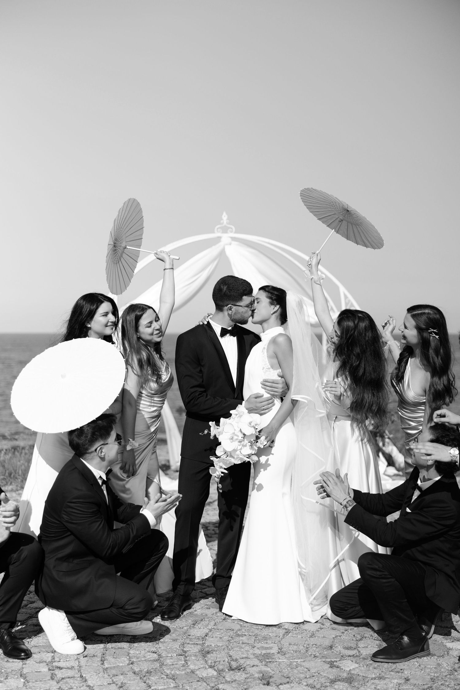 Black and white wedding photo series showing a sequence of couples holding parasols and sharing romantic moments outdoors.