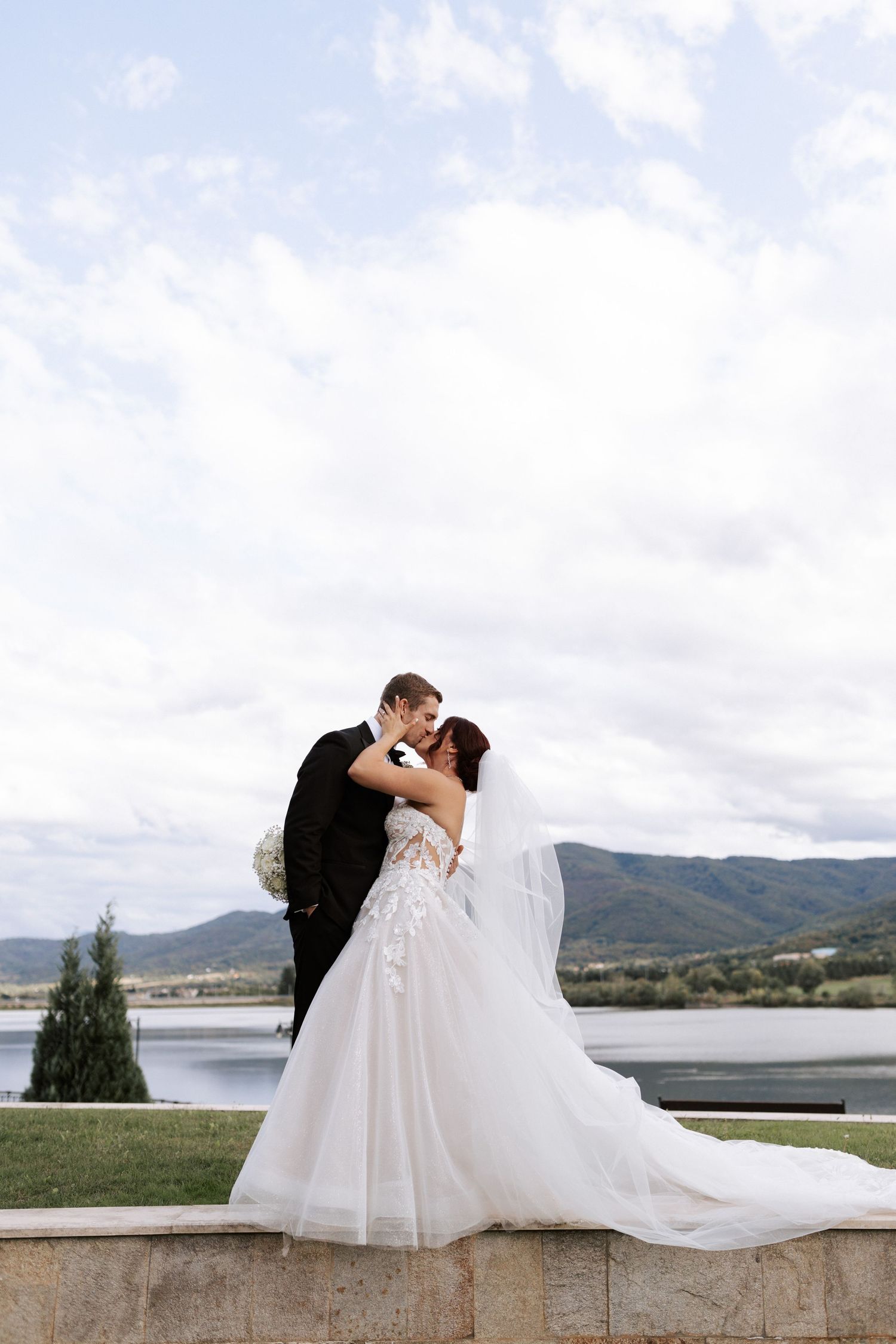 Romantic wedding portrait against mountain lake backdrop.