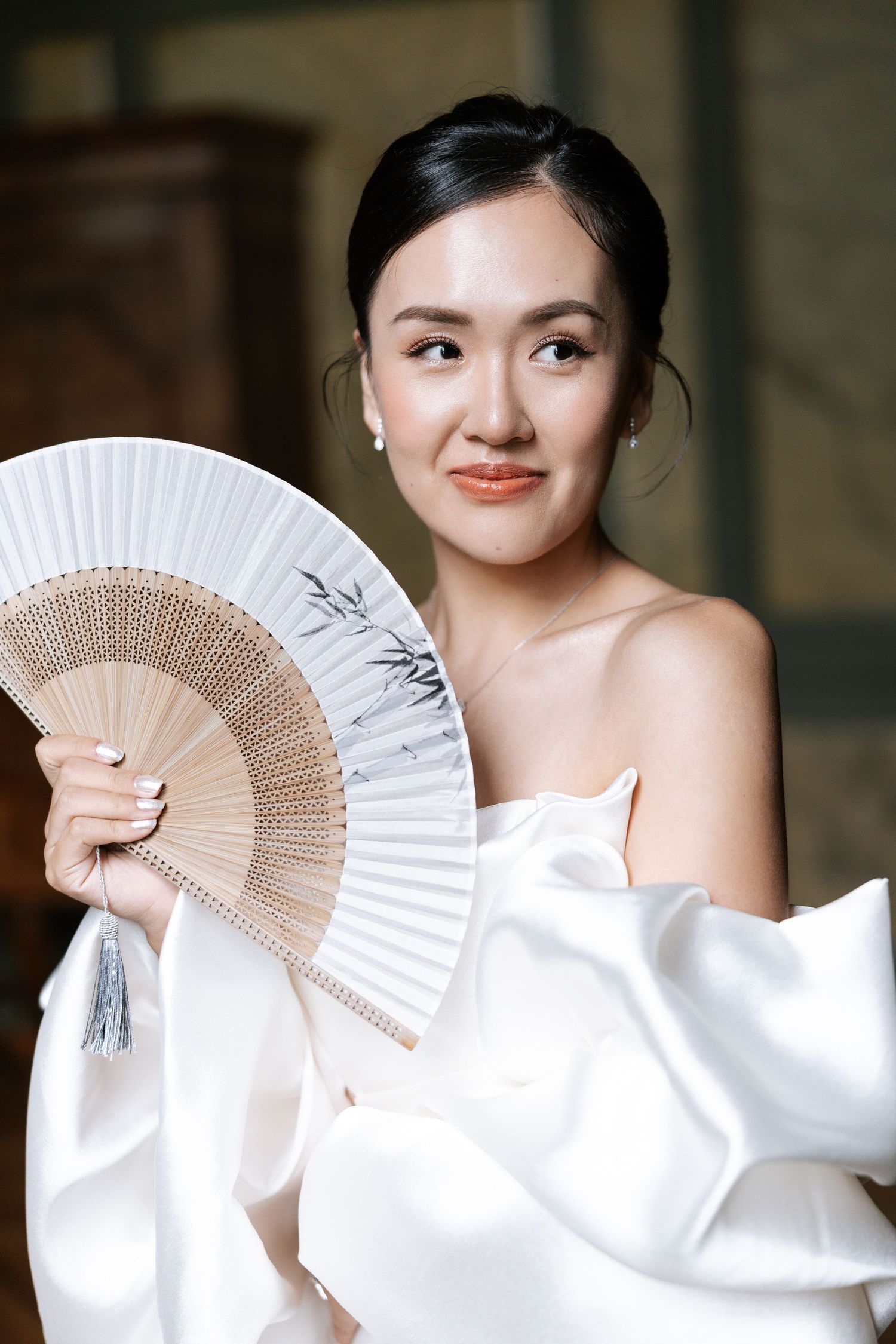 A series of elegant bridal portraits featuring traditional hand fans and flowing white fabric in a soft, romantic setting.