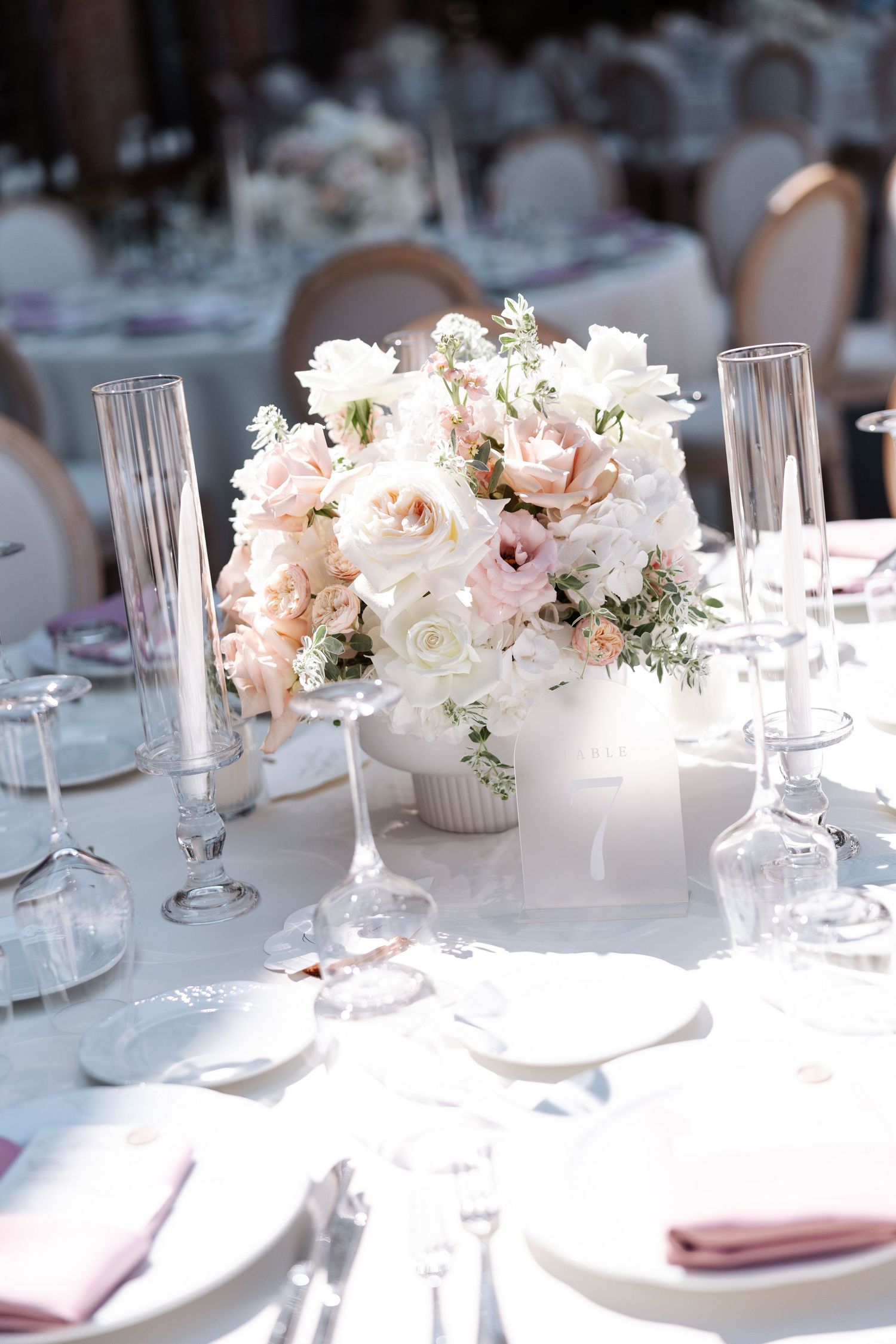Elegant table settings with blush pink and white floral centerpieces and crystal glassware.