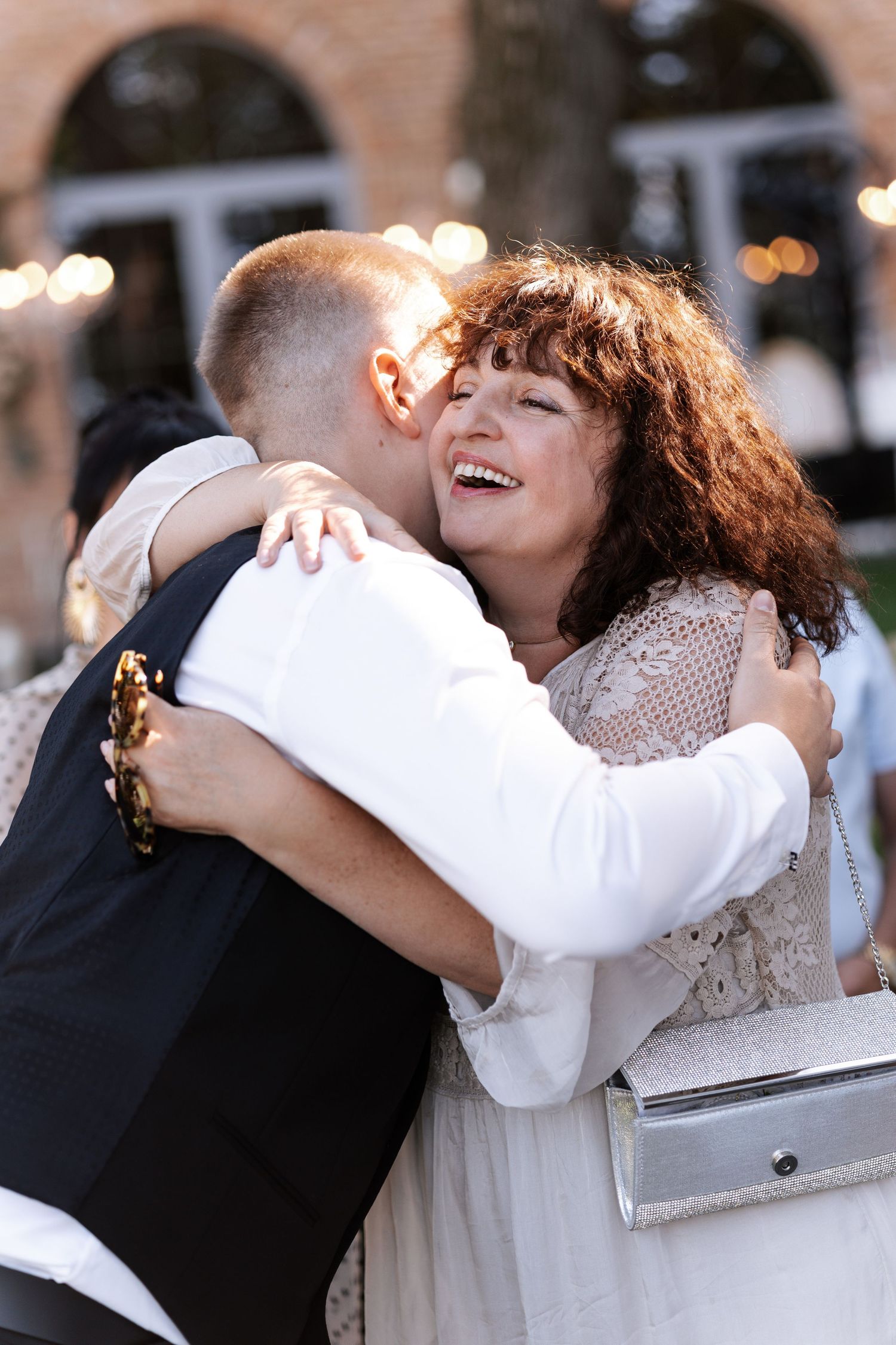 Wedding guests sharing joyful embraces and dancing during an outdoor celebration.