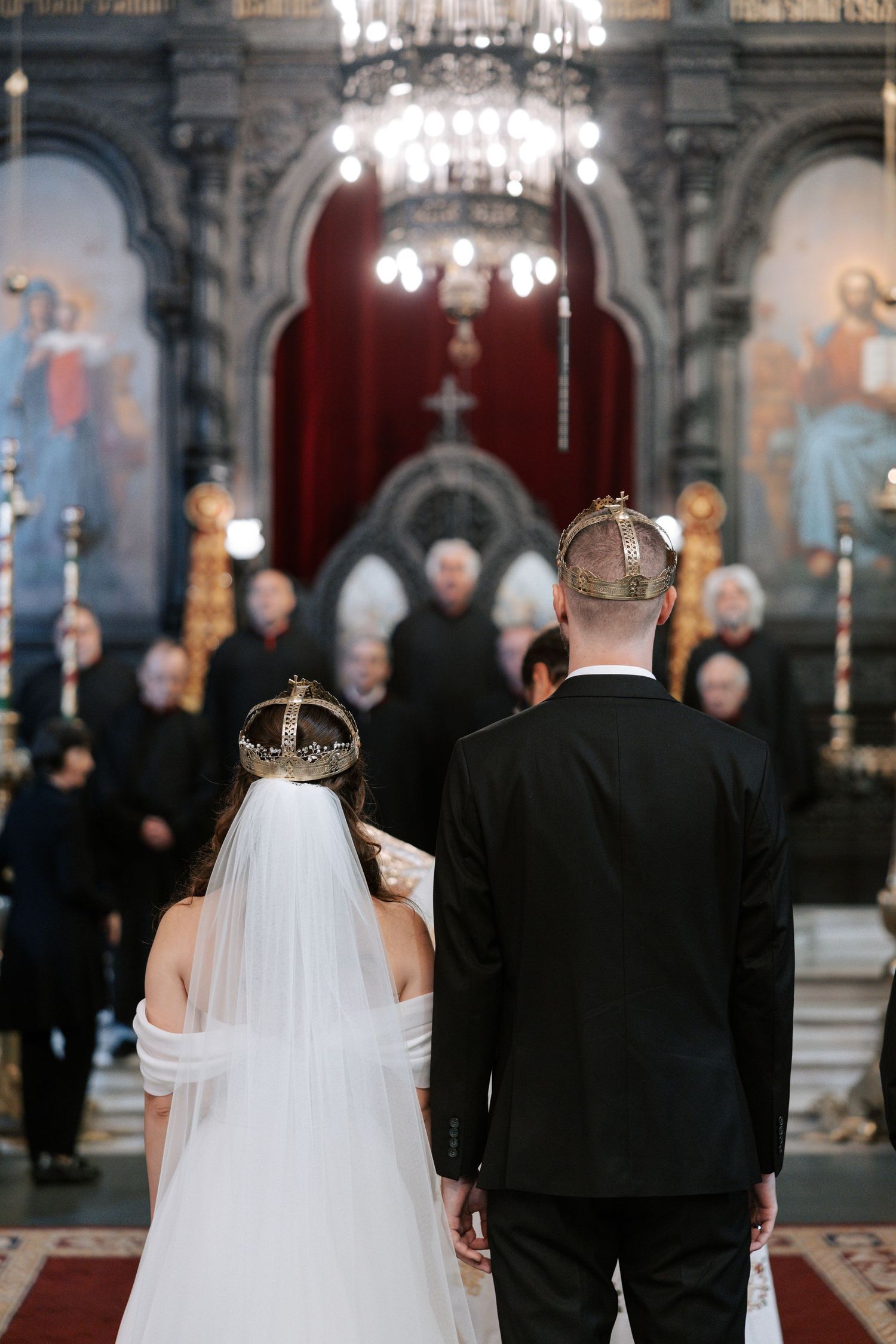 Couple stands before an Orthodox iconostasis during their traditional church wedding ceremony.
