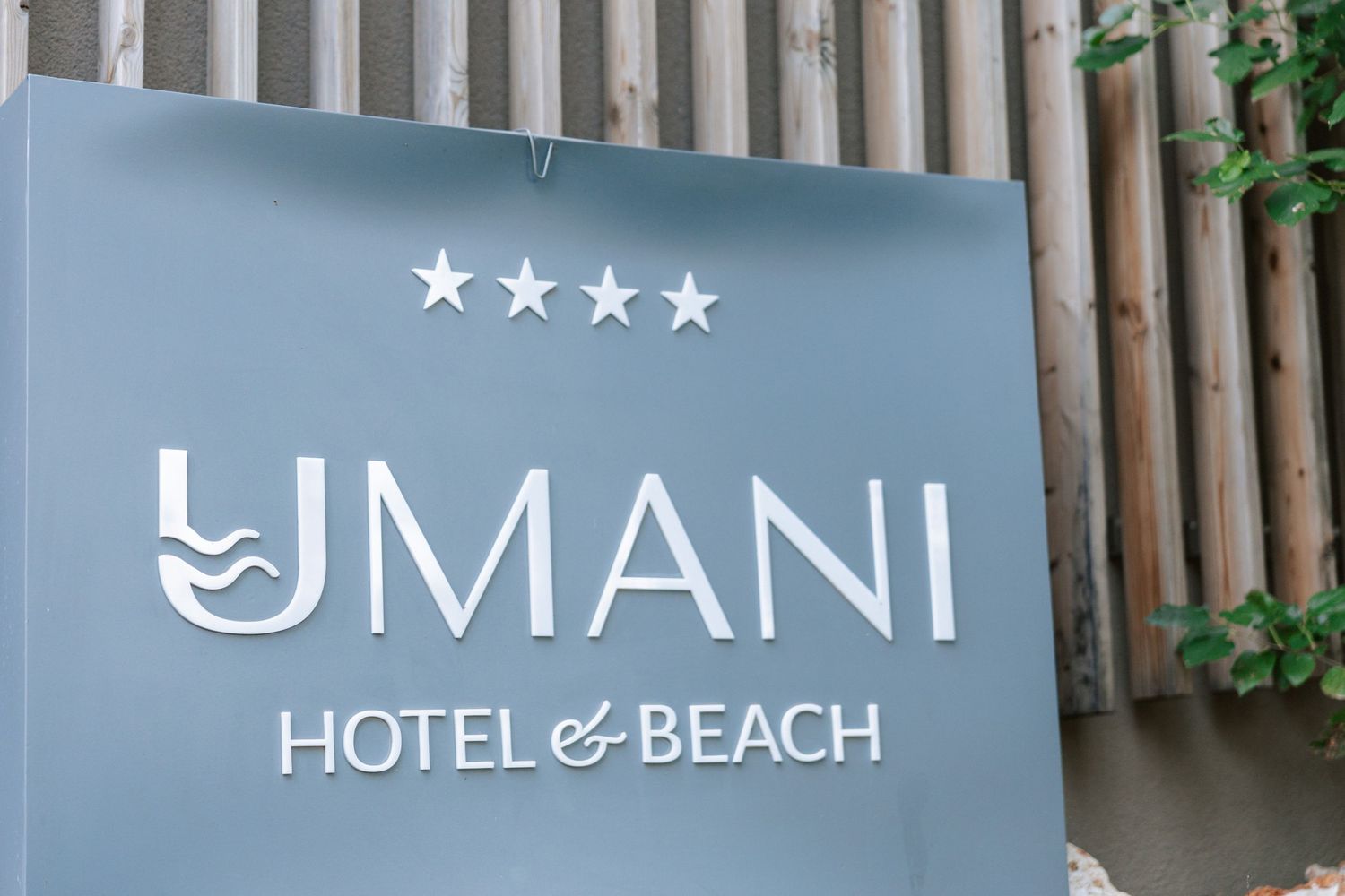 A sign for the four-star Umani Hotel & Beach with modern design elements.