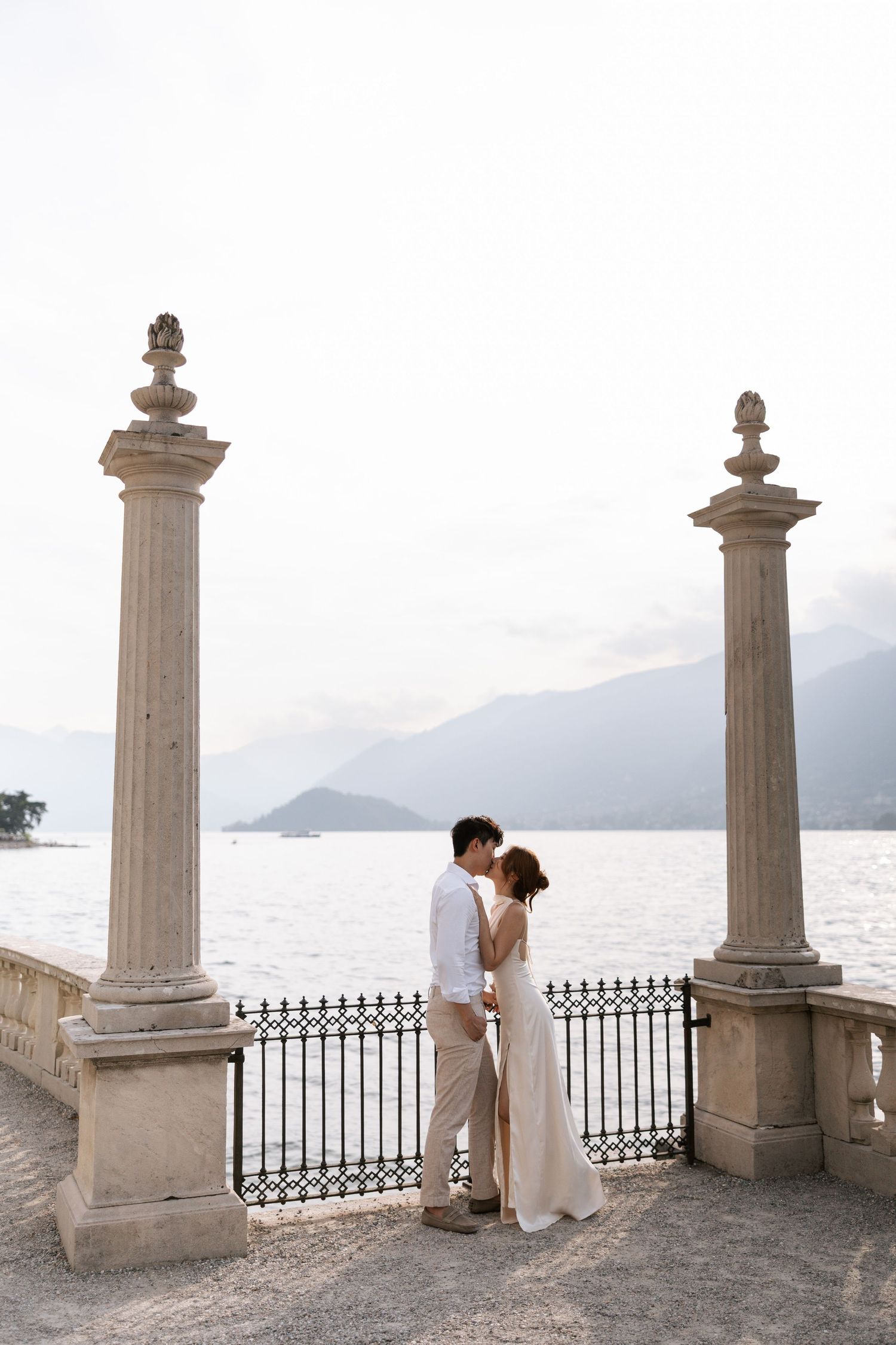 Romantic wedding photo shoot at a Mediterranean balcony with stone pillars overlooking the sea.