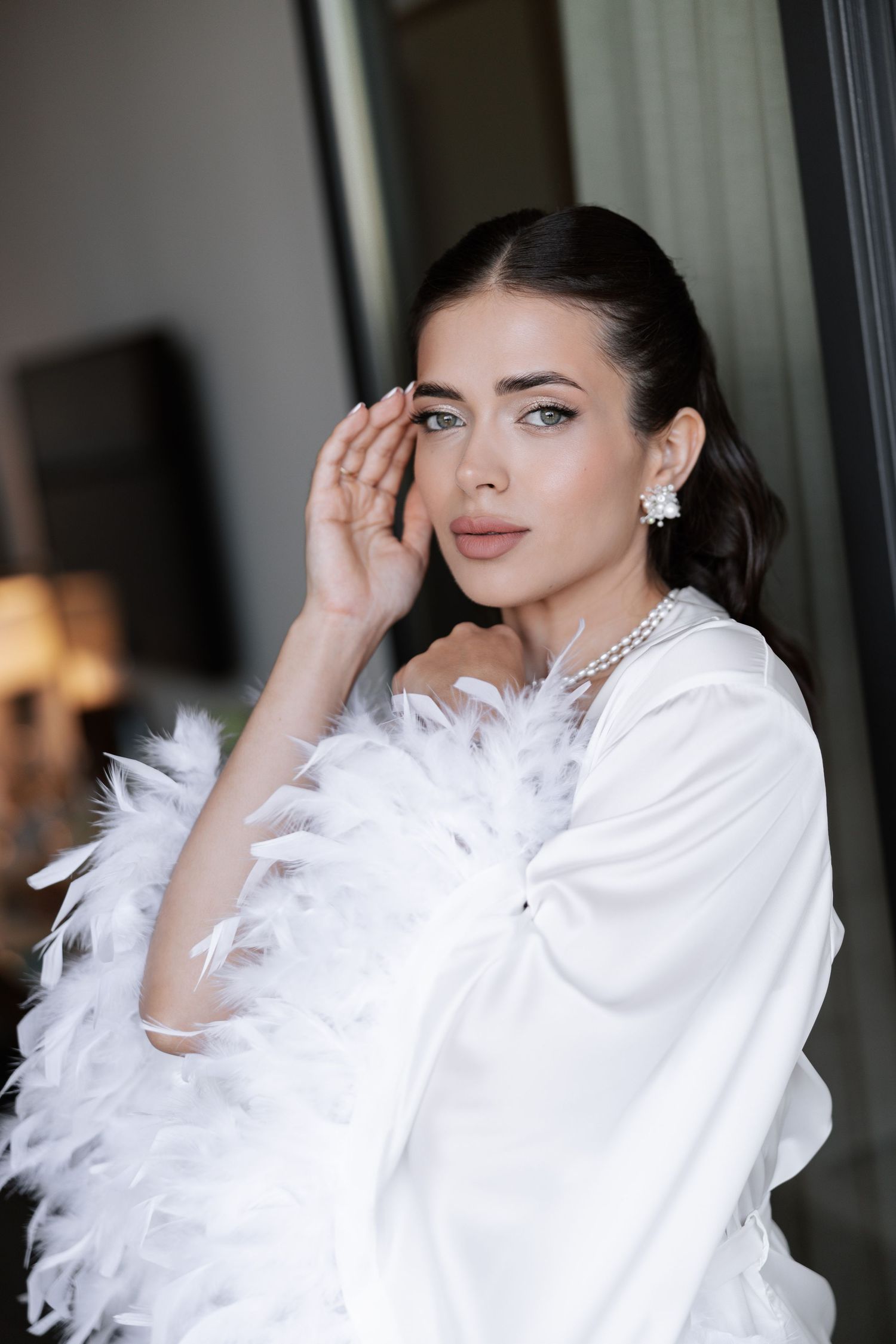 Person in white ruffled outfit with dramatic feather details poses elegantly in a series of profile shots.