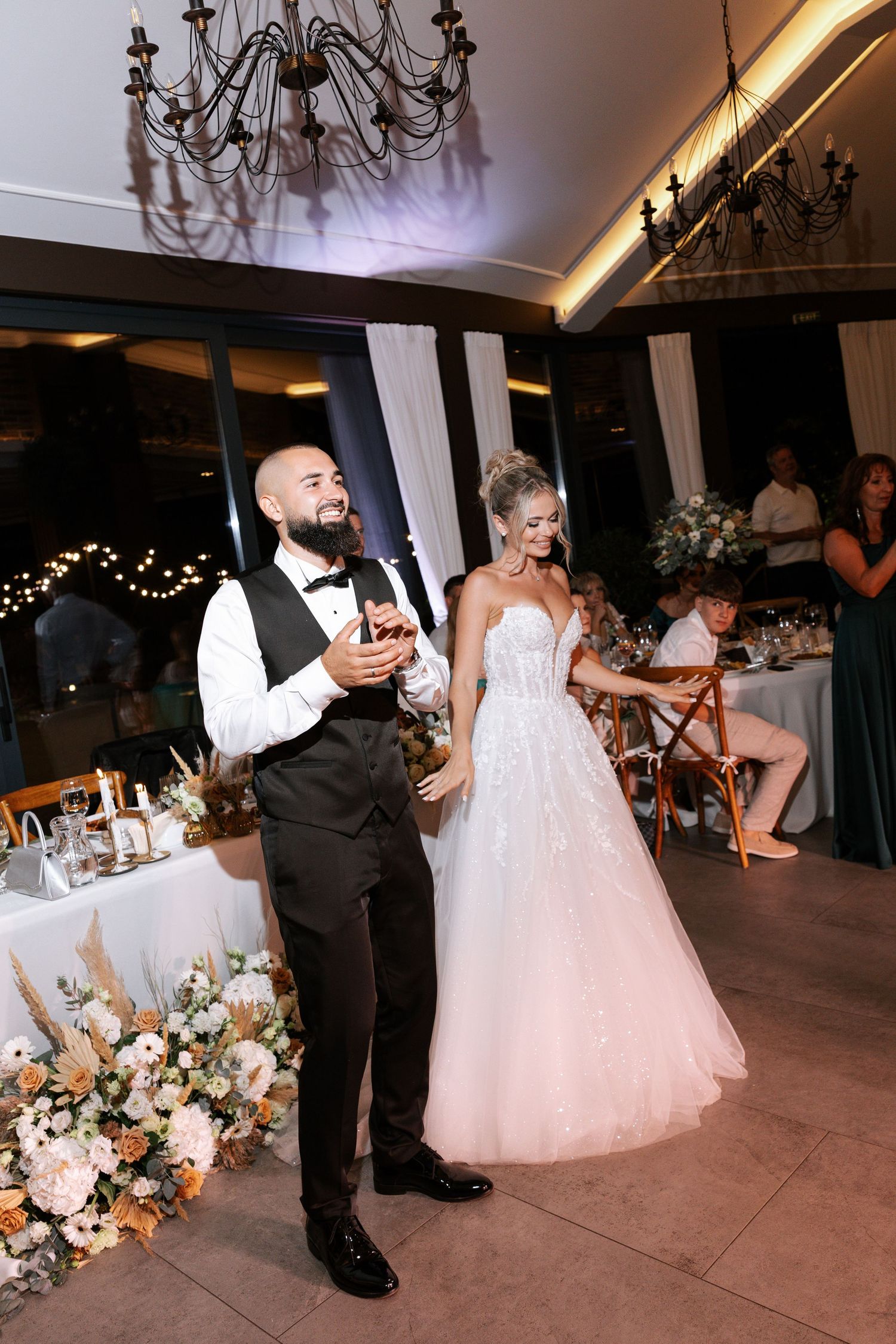 Wedding couple dancing together on the dance floor during their reception celebration with elegant decor and lighting.