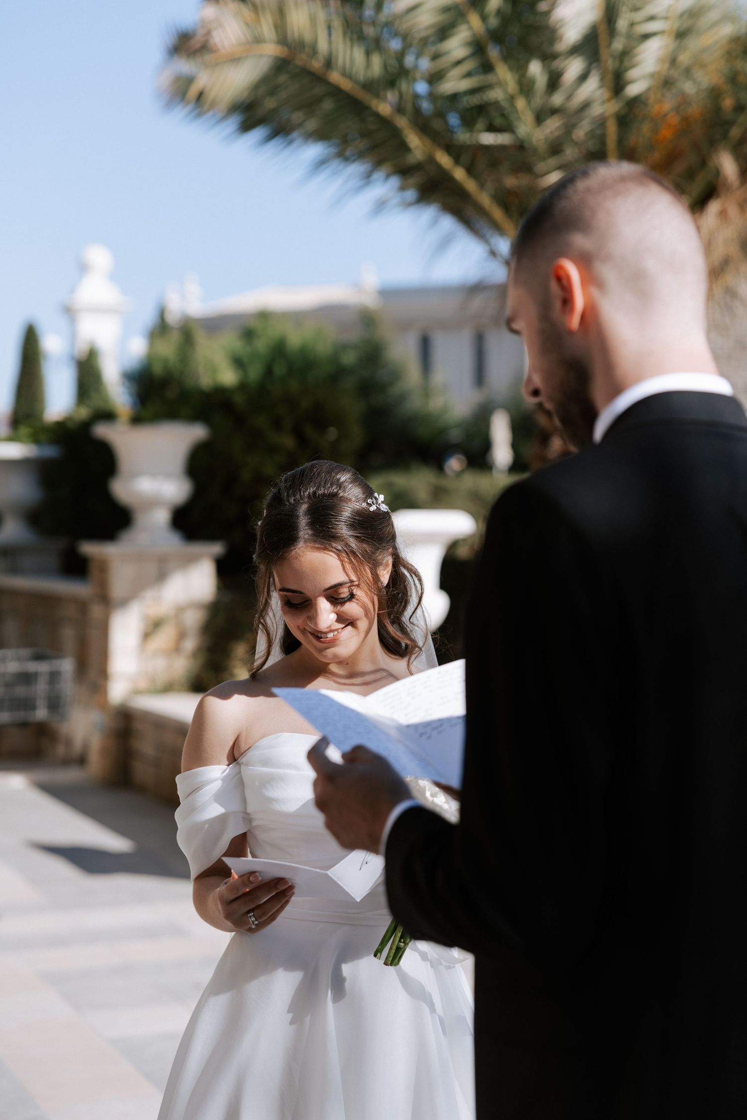 A couple sharing intimate moments while reading their vows in an outdoor ceremony.
