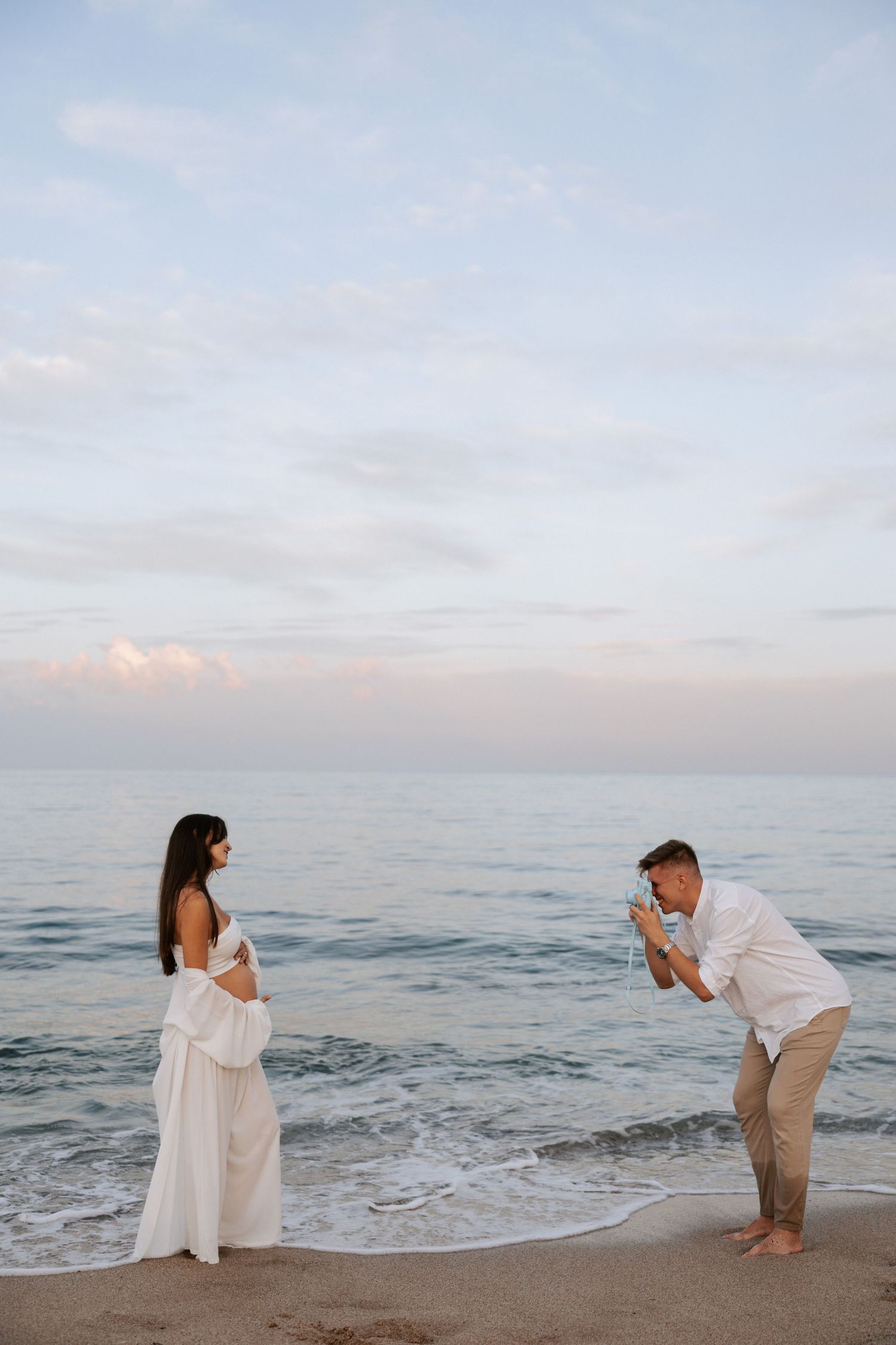 A romantic beachside pregnancy announcement photoshoot at sunset.