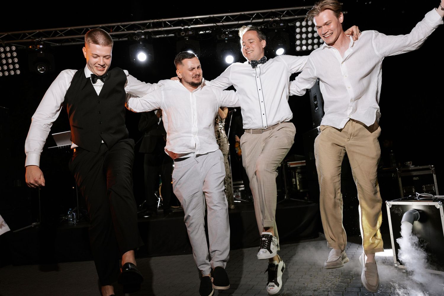 Group of wedding guests performing choreographed dance moves on stage.