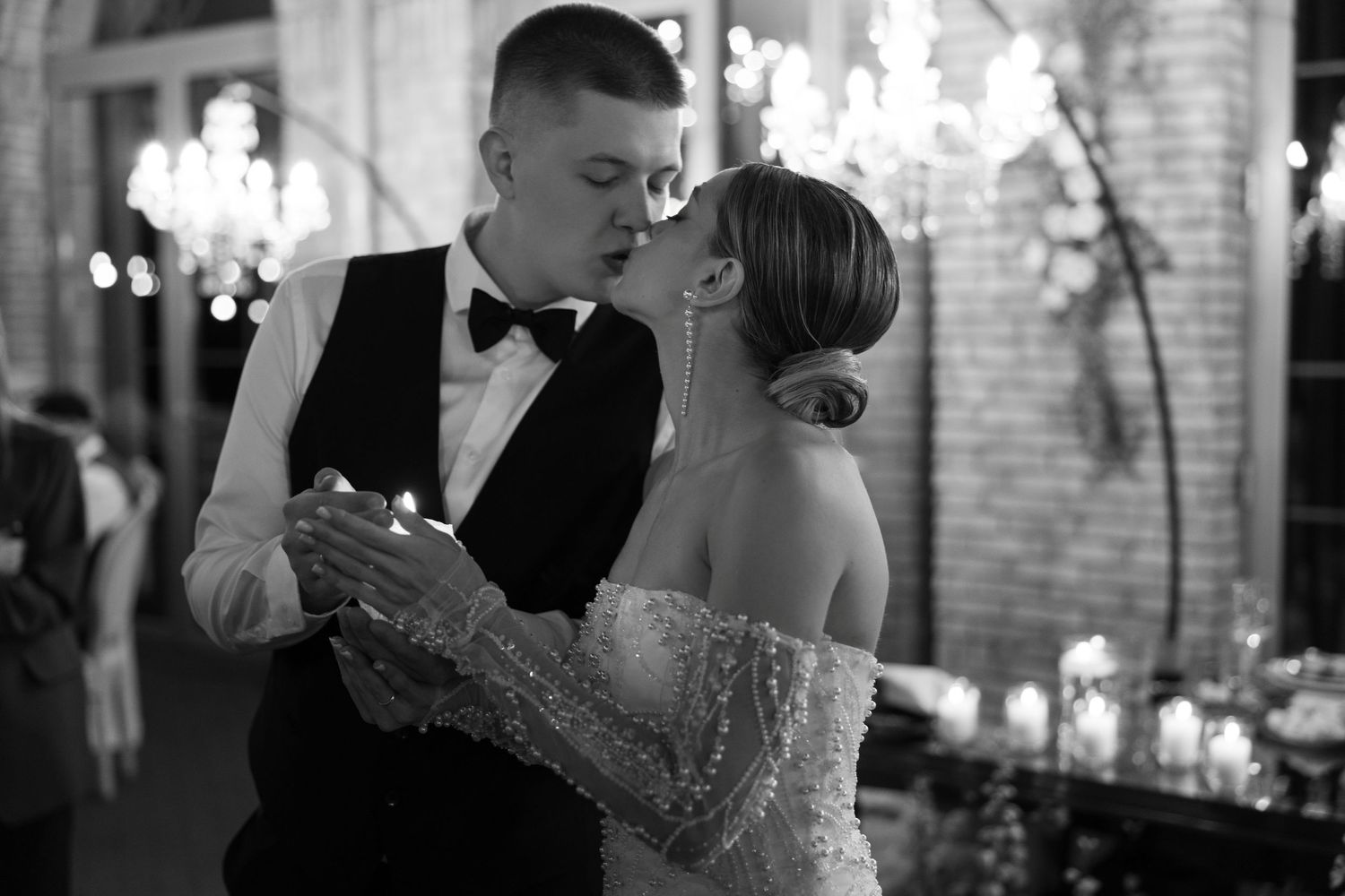 Intimate black and white dance moment at wedding reception with chandeliers.