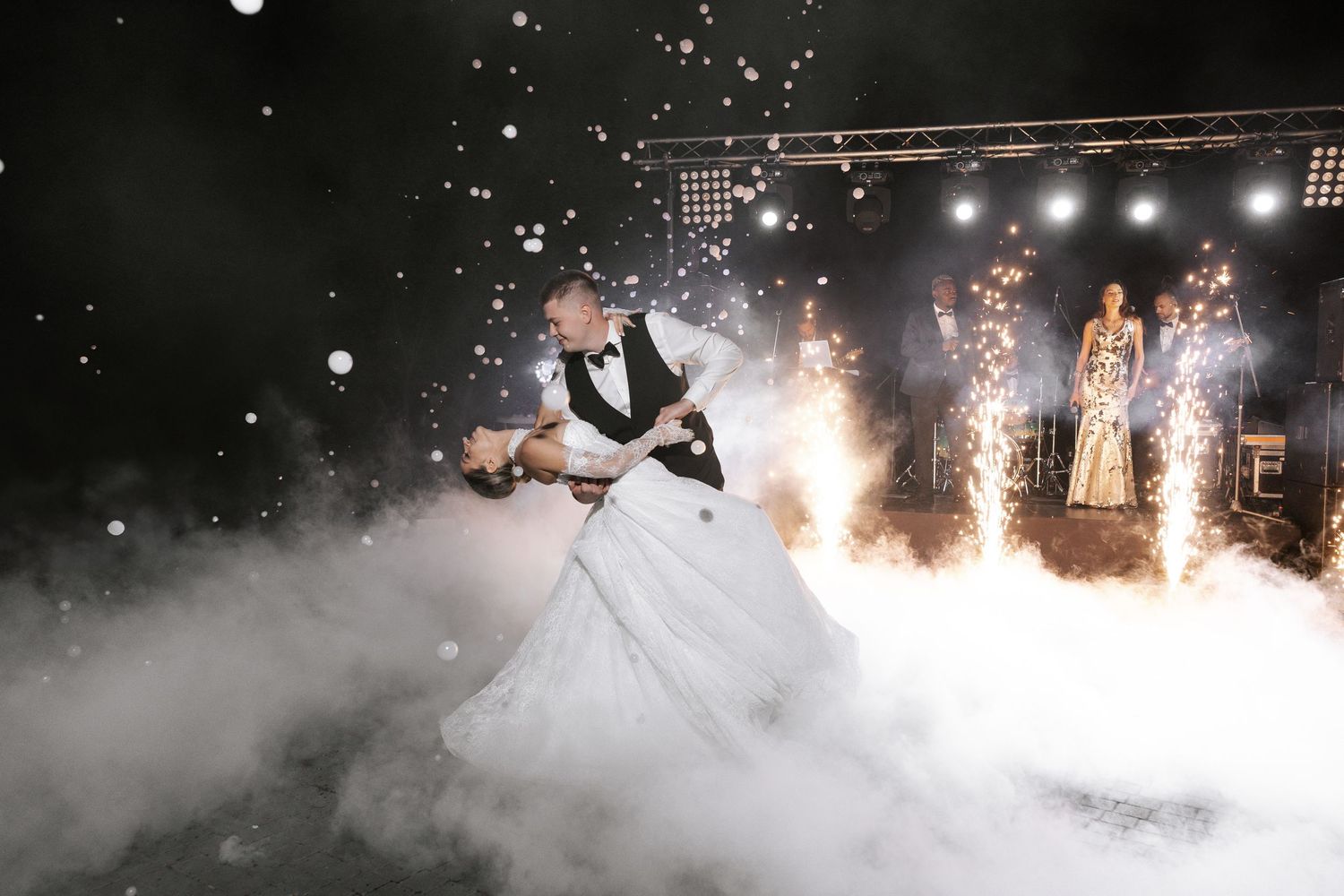Couple dancing through theatrical fog and sparkler effects at their wedding reception.