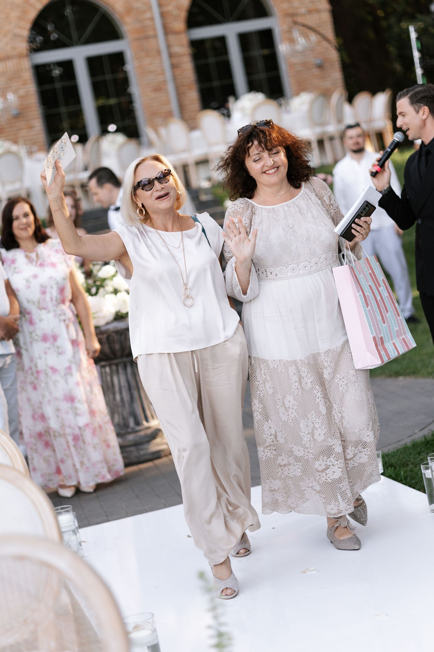 Wedding party members in white and floral attire walking down outdoor pathway.
