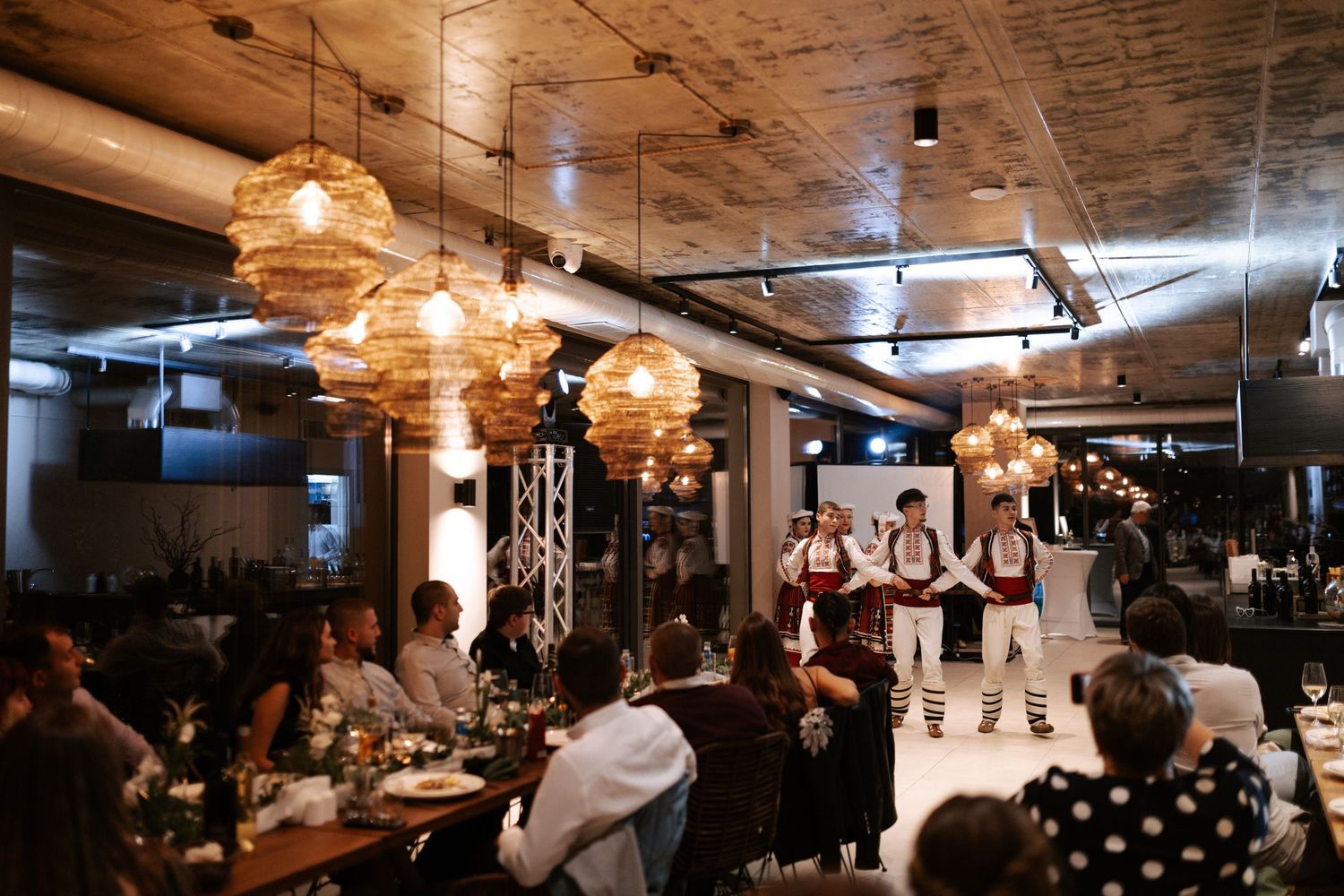 Elegant reception venue with warm lighting from woven pendant lamps and exposed ceiling beams.