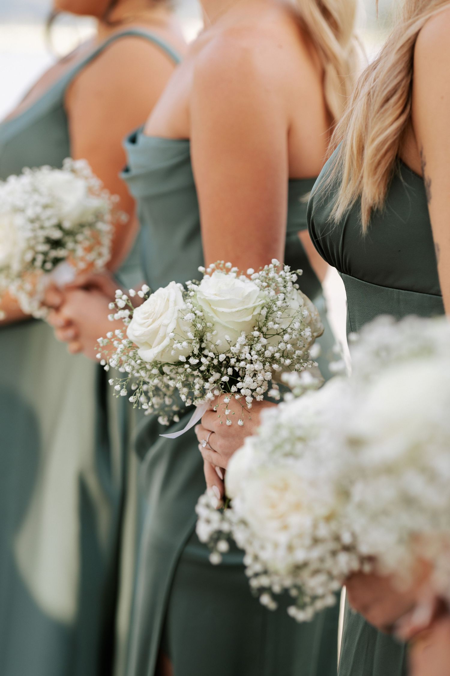 Close-up of bridesmaids holding white rose and baby's breath bouquets.