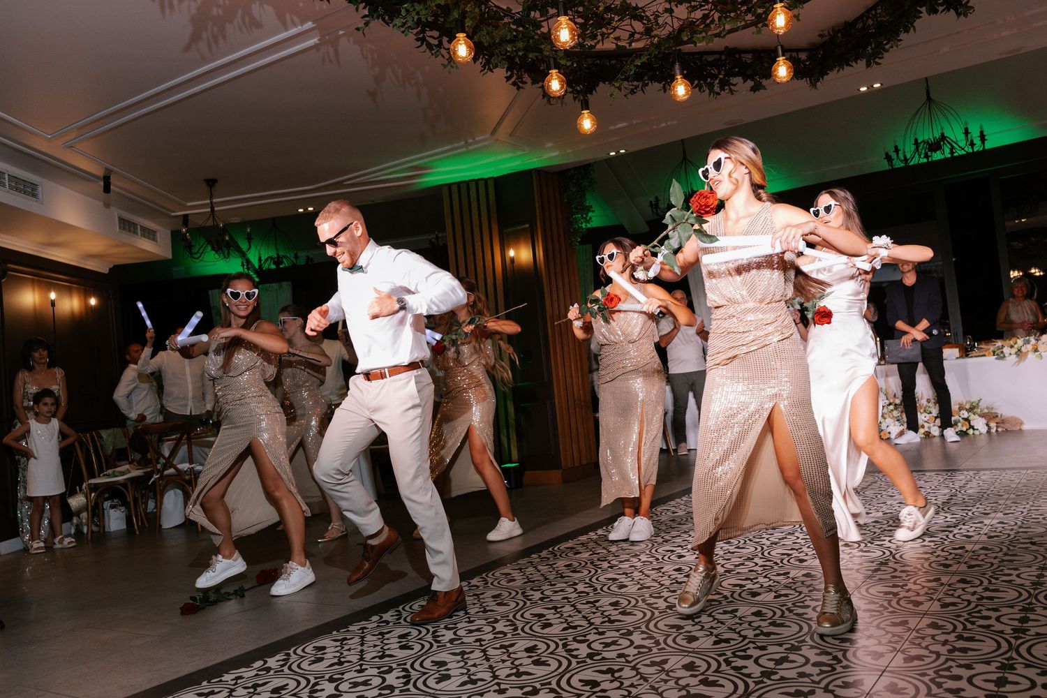 Dancers perform dynamic breakdancing moves on a patterned floor under warm lighting at an indoor event.
