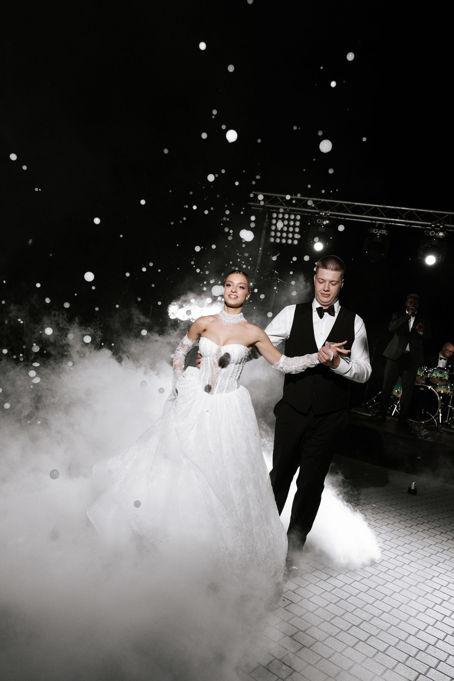 A couple performs their first dance at a wedding reception surrounded by dramatic fog effects on the dance floor.