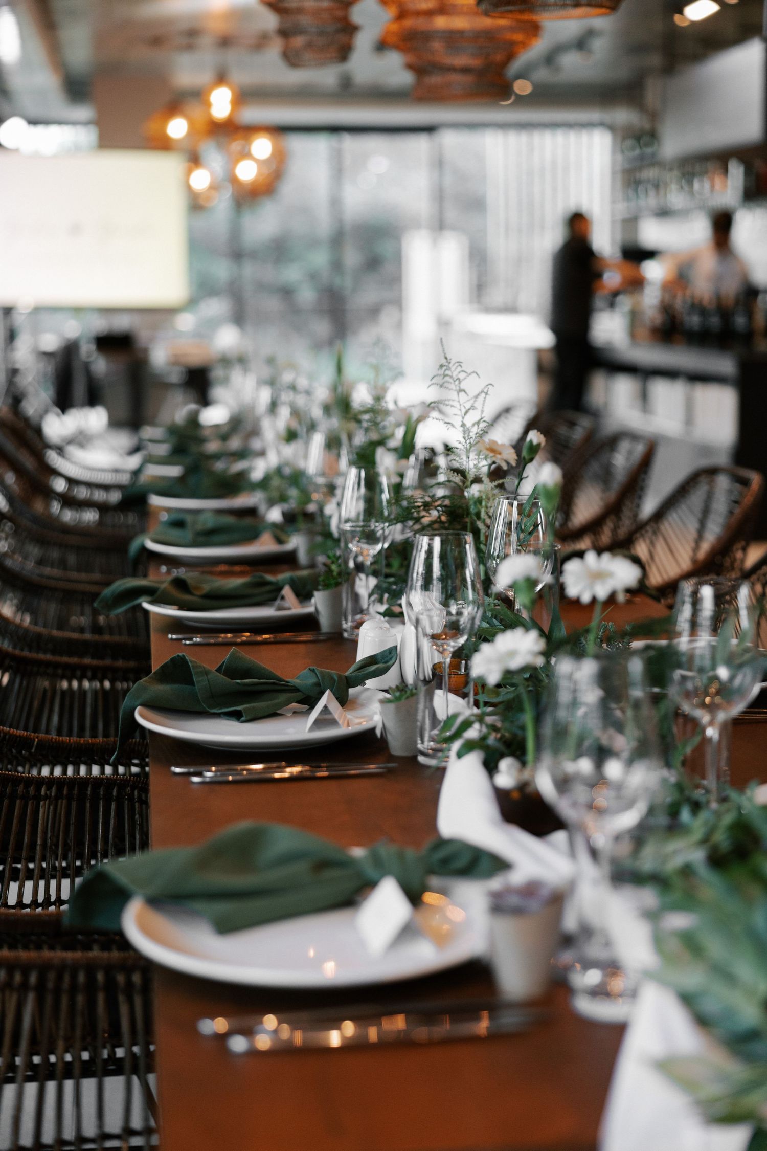 Formal table setting with green napkins, white plates and delicate floral centerpieces.