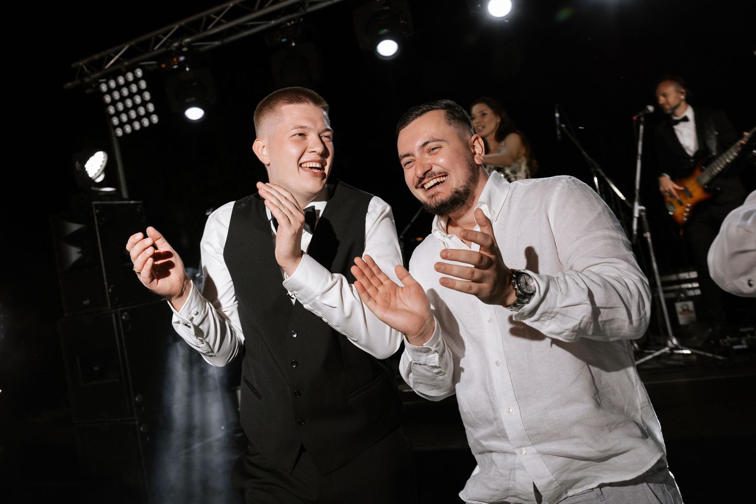 Wedding guests dancing and celebrating at a dimly lit evening reception.