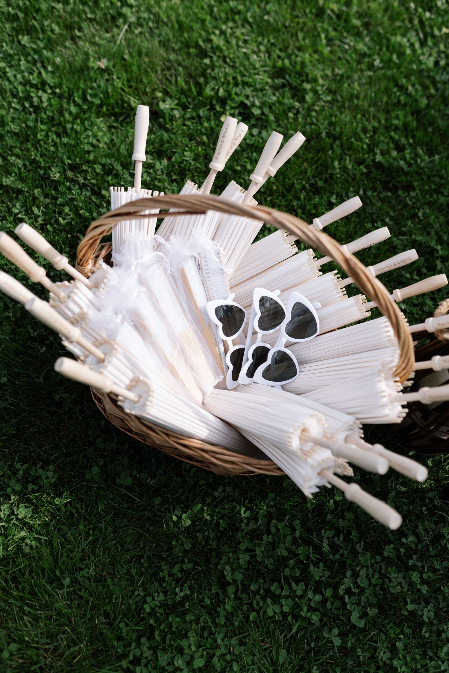 A woven basket filled with white paper scrolls and black silhouette designs arranged in a fan pattern on green grass.