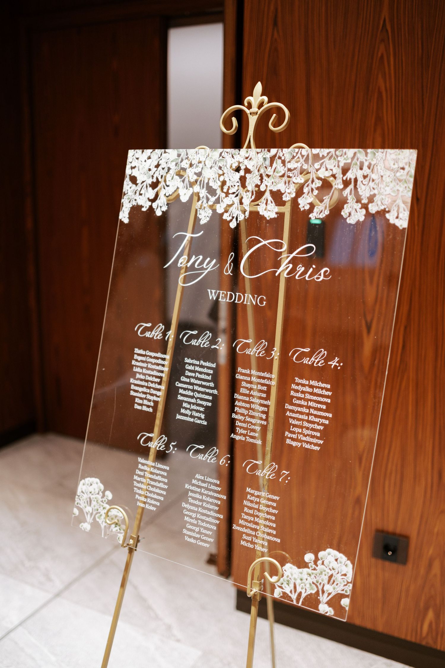 Elegant acrylic wedding seating chart with lace details and gold stand.