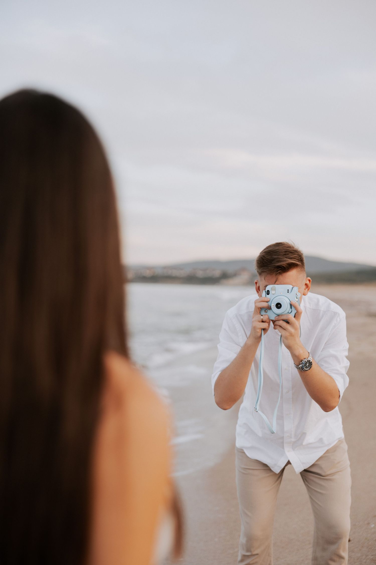 A beachside photoshoot with someone taking pictures with a vintage camera.