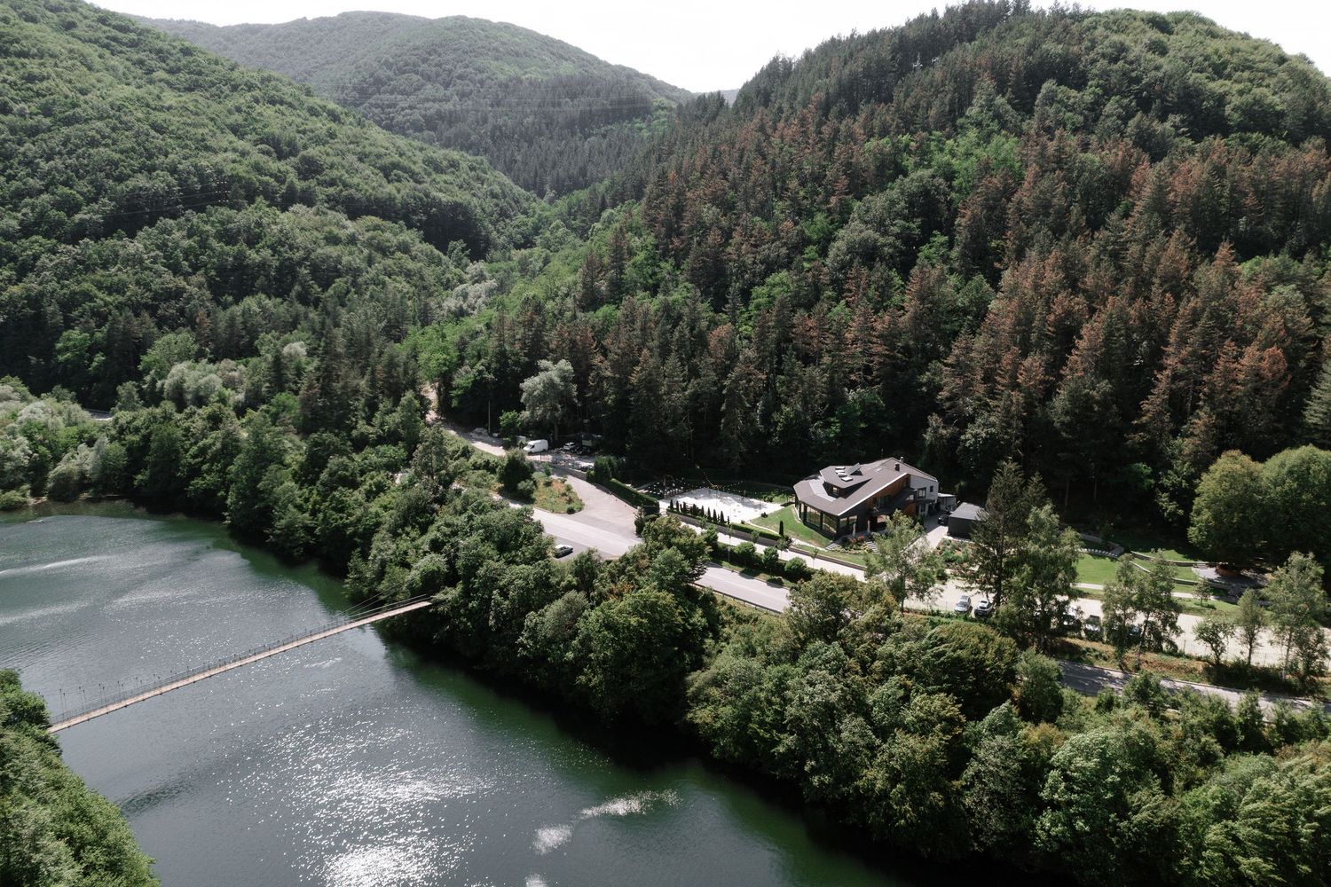 Aerial view of a winding river surrounded by dense forest and mountains in a scenic natural landscape.