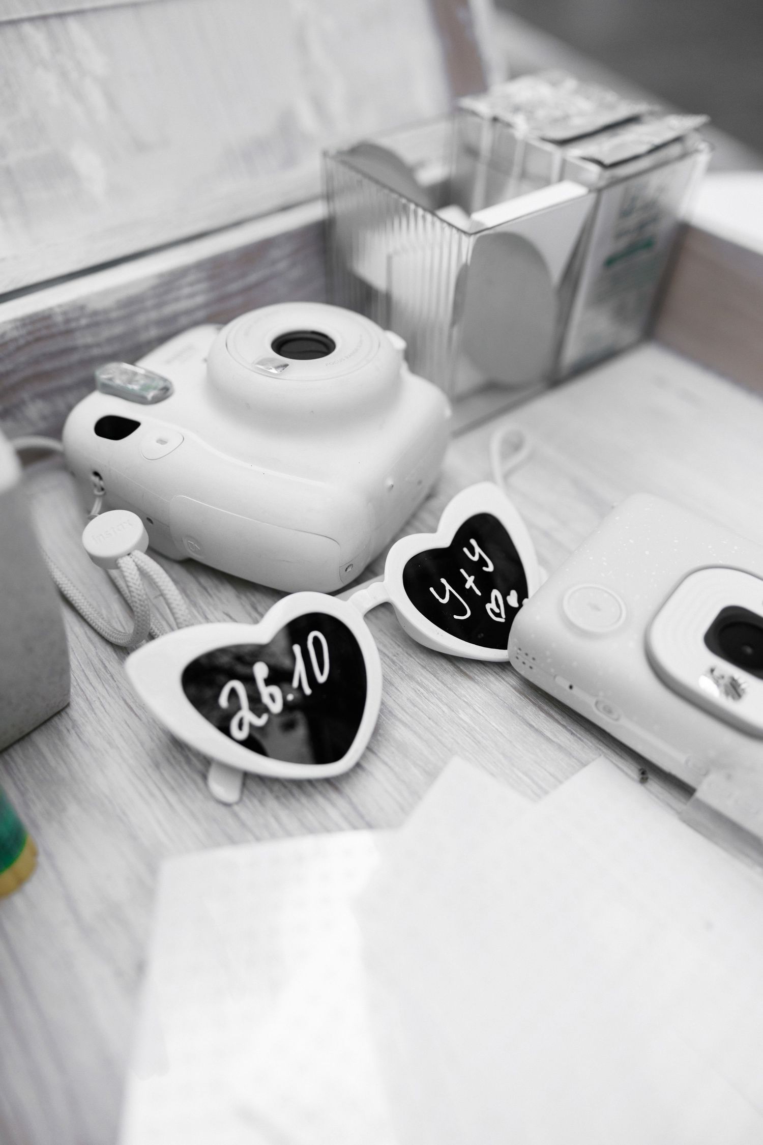 White Instax camera with heart-shaped date cards in black and white.