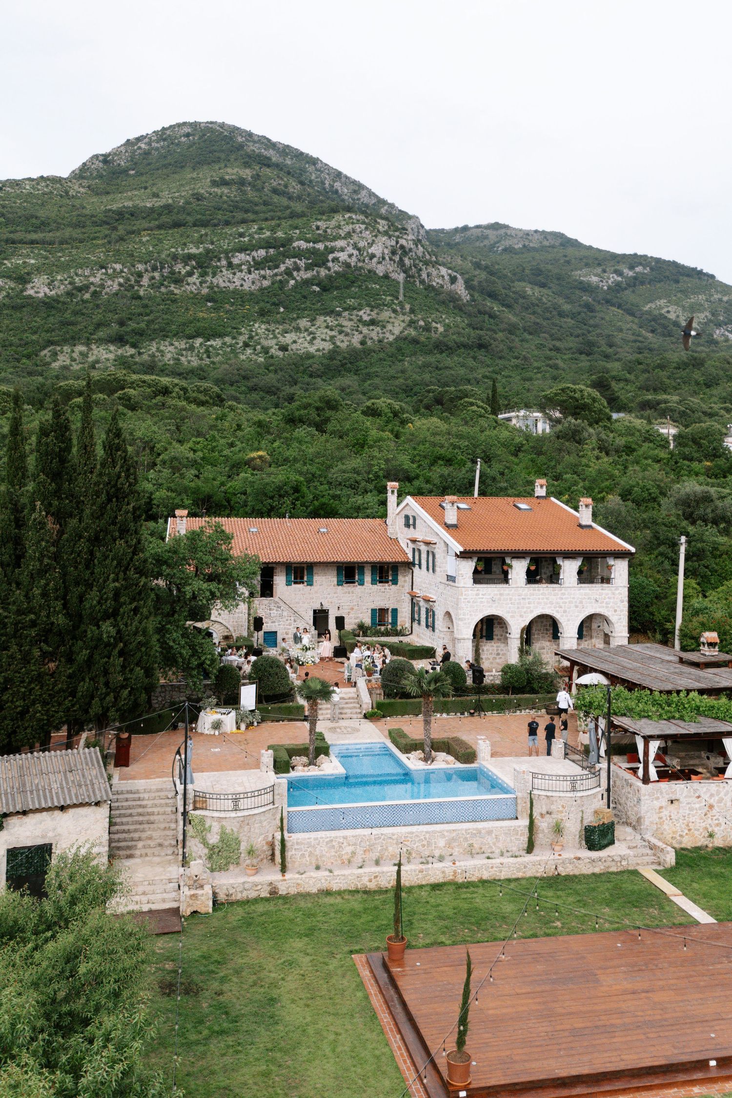 Mediterranean villa with swimming pool and terrace nestled in lush green mountainside landscape.