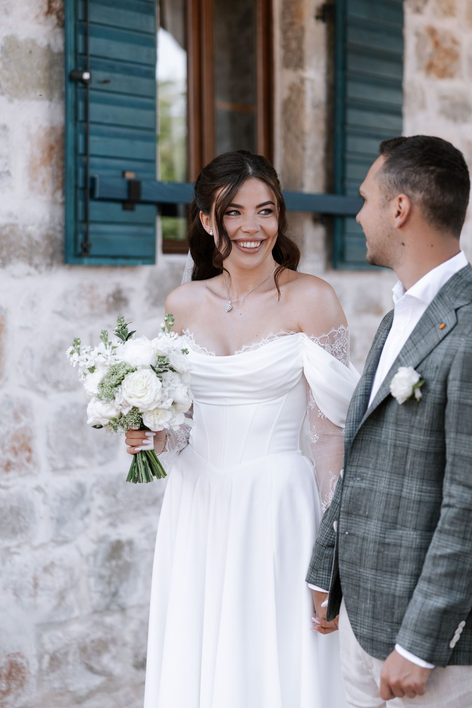 A series of candid wedding photos showing a couple in white dress and grey suit against a rustic stone wall.