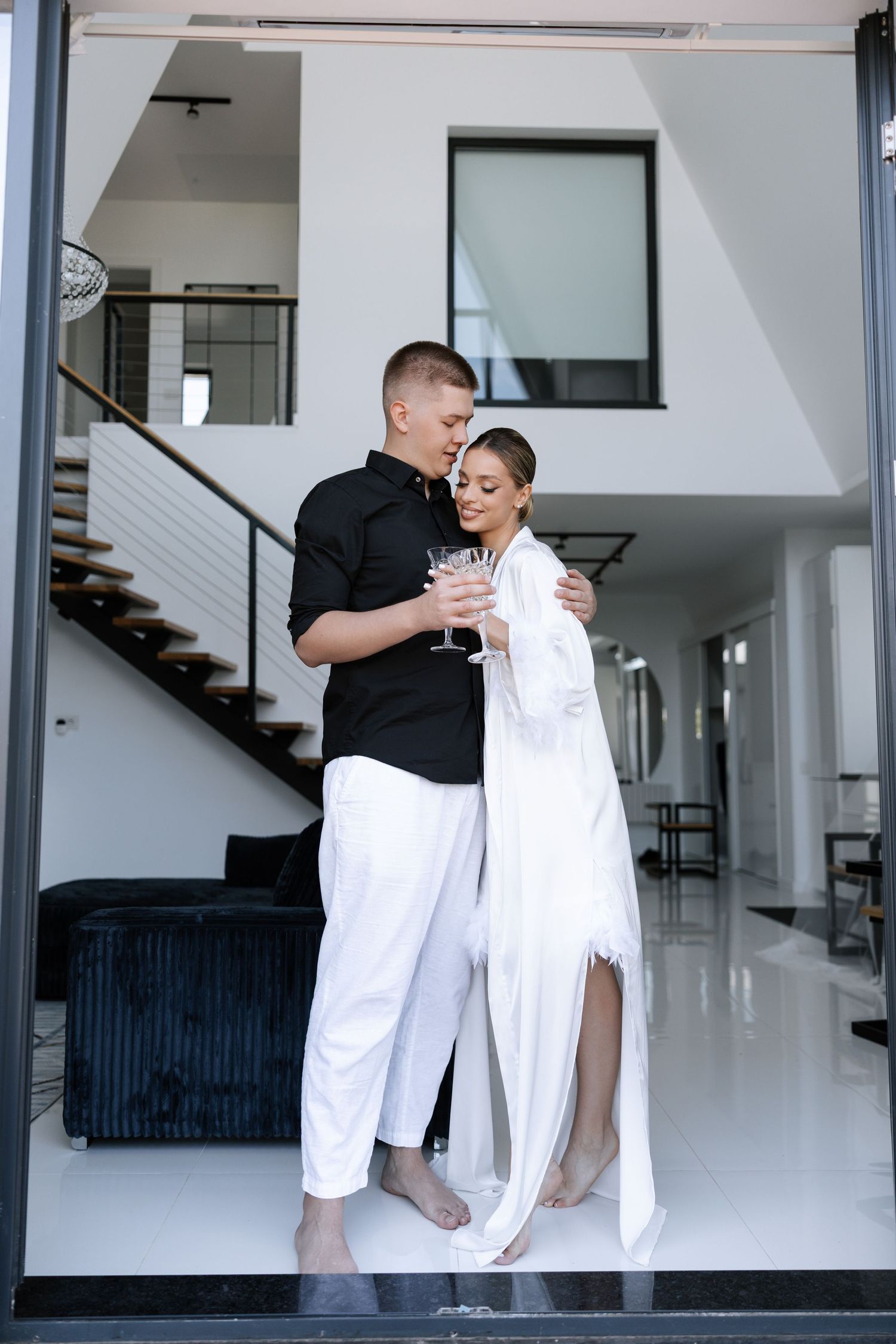 Couple in contrasting black and white outfits standing in a modern minimalist interior.