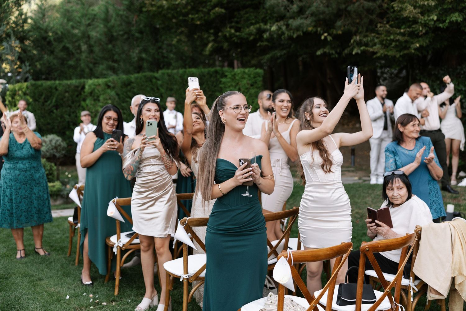 Wedding guests dance joyfully in an outdoor garden setting during a summer celebration.