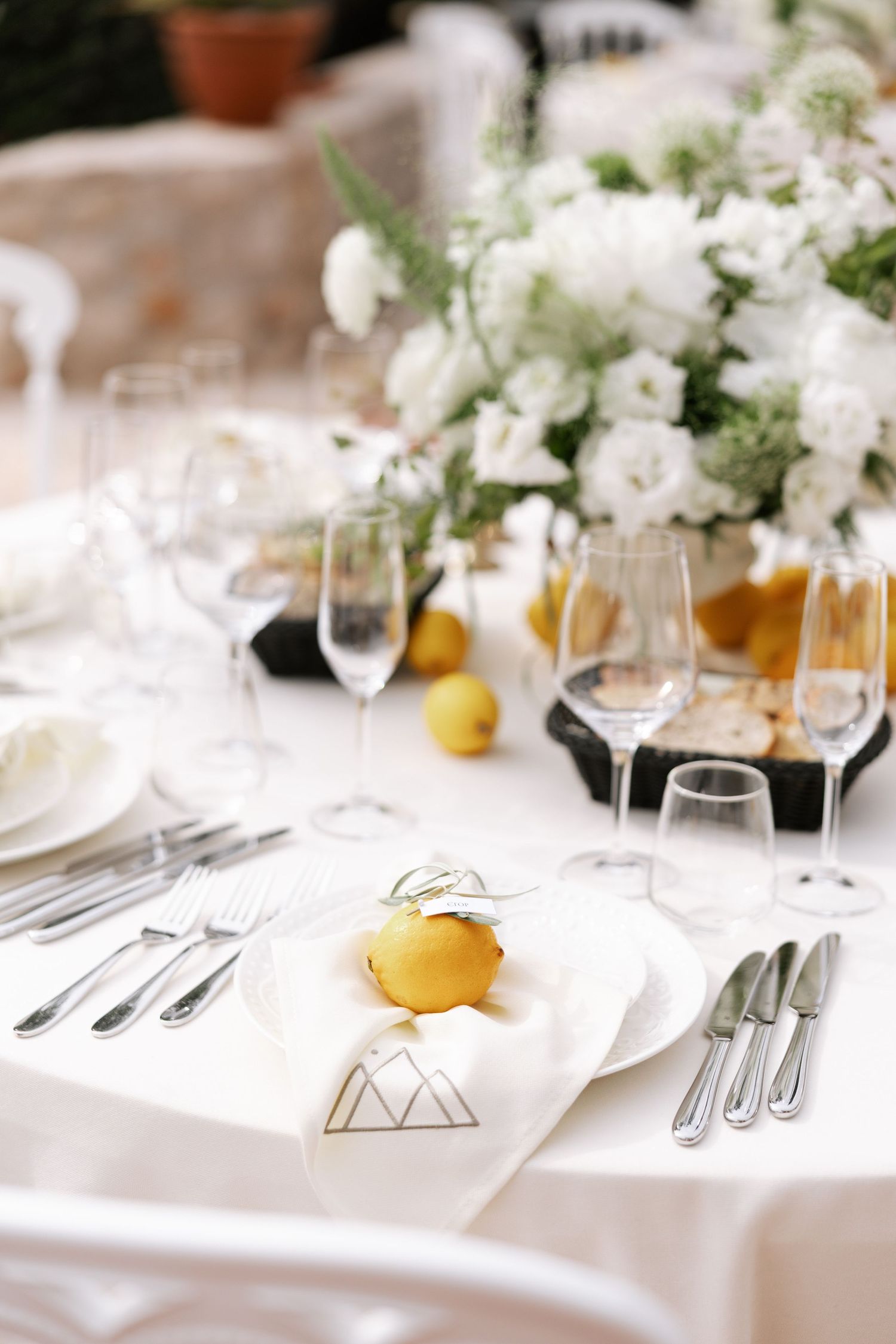 Elegant white table setting with fresh lemons and white flowers for a formal dining event.