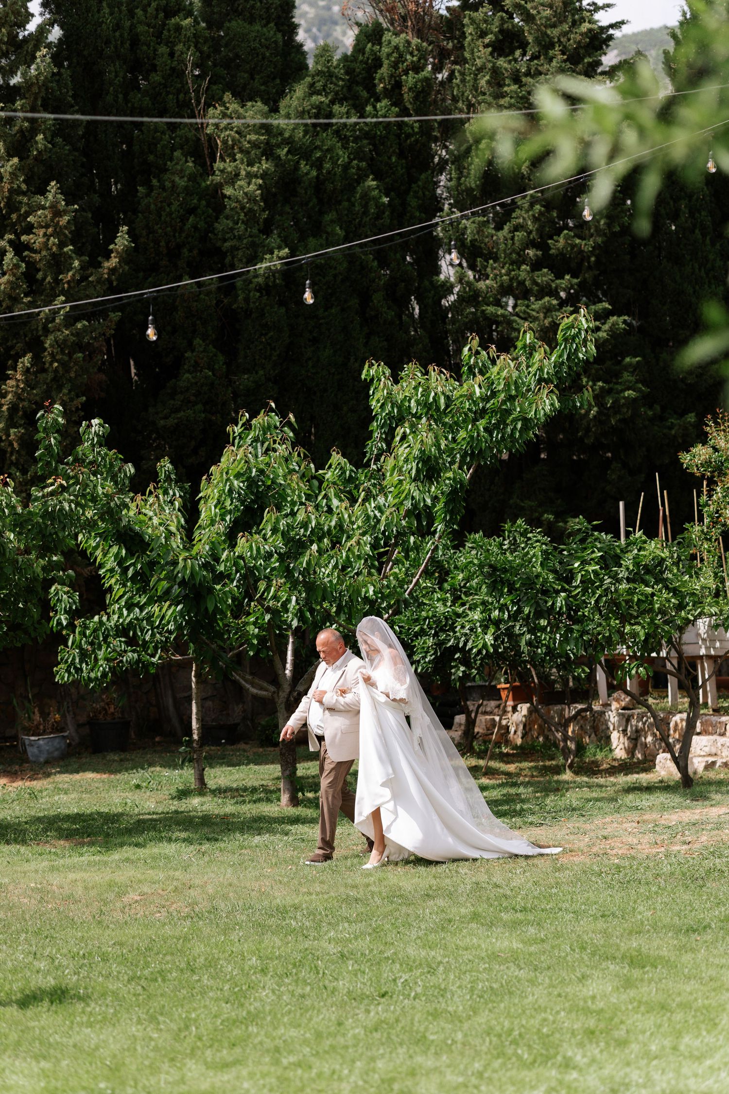 A couple walks through a lush garden setting during an outdoor wedding photoshoot.