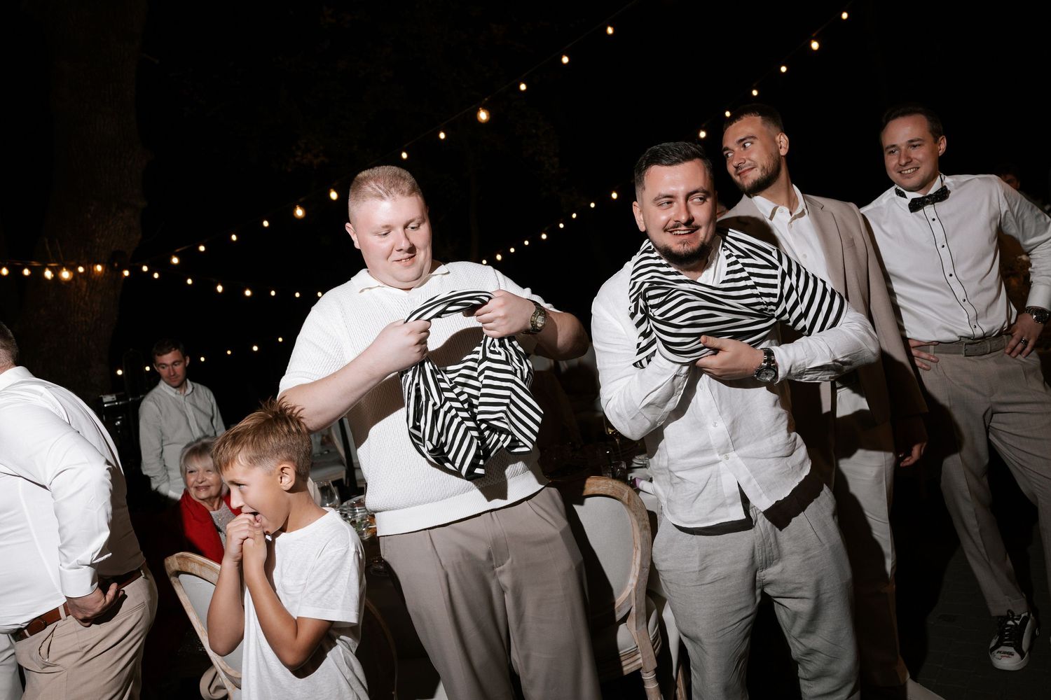 Wedding party dancing and celebrating during nighttime reception.