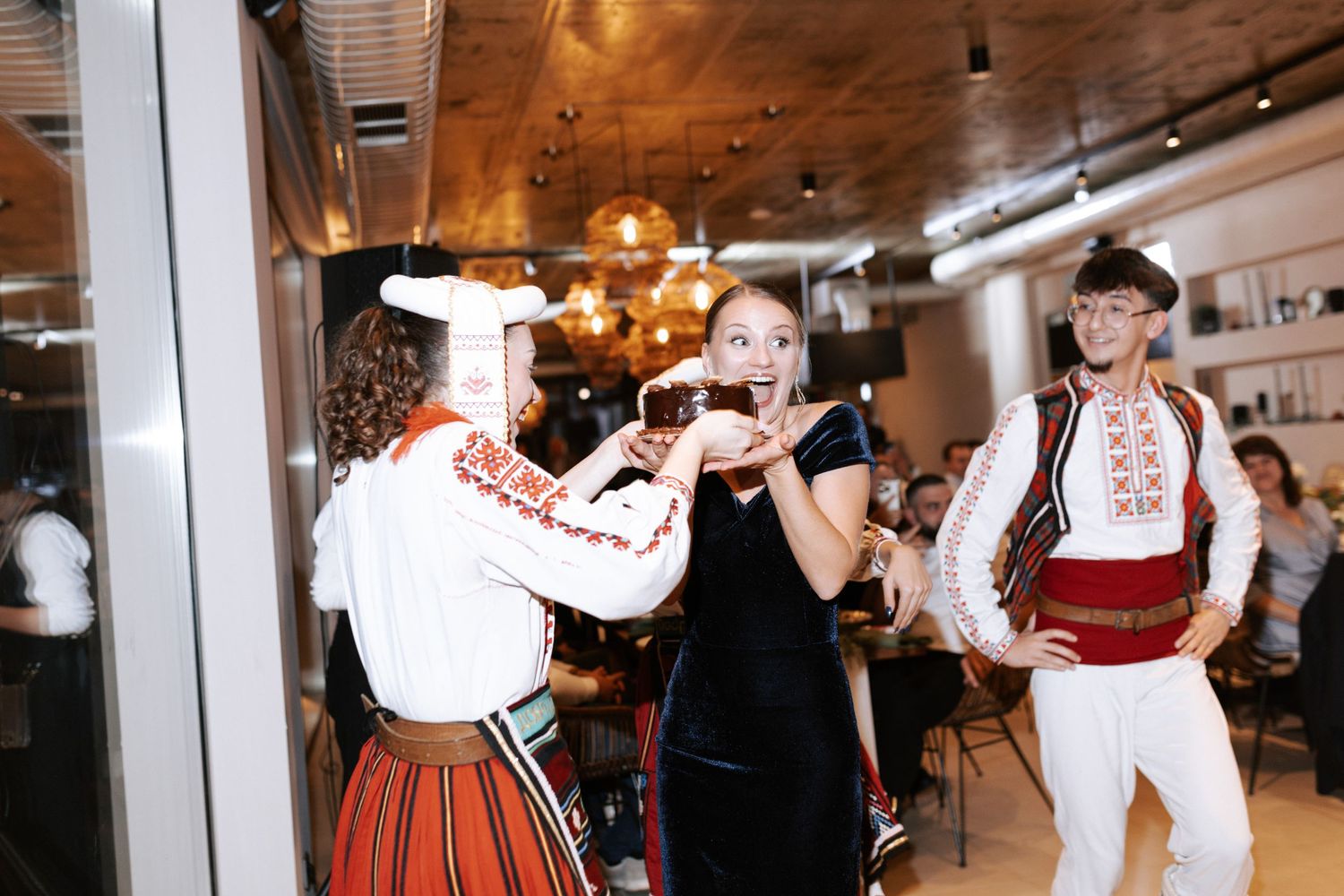 Traditional folk dancers in cultural costumes performing at an indoor event venue.